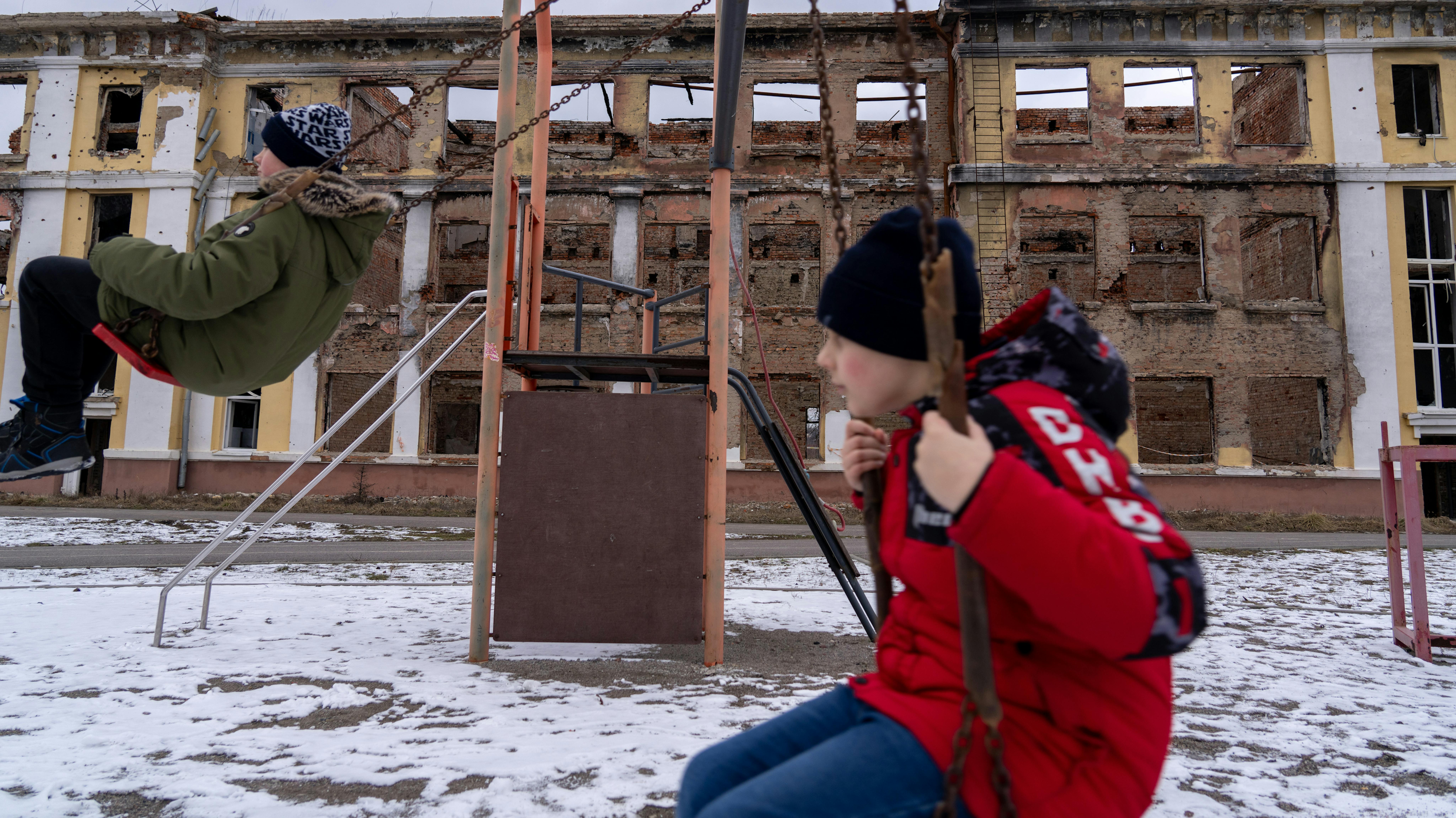 Yaroslav, 11 anni, e la sua amica Ilia, 11 anni, giocano su un'altalena tra le rovine della scuola n. 134, nota anche come Liceo di Kharkiv n. 134, situata in via Shevchenka, 220 a Kharkiv