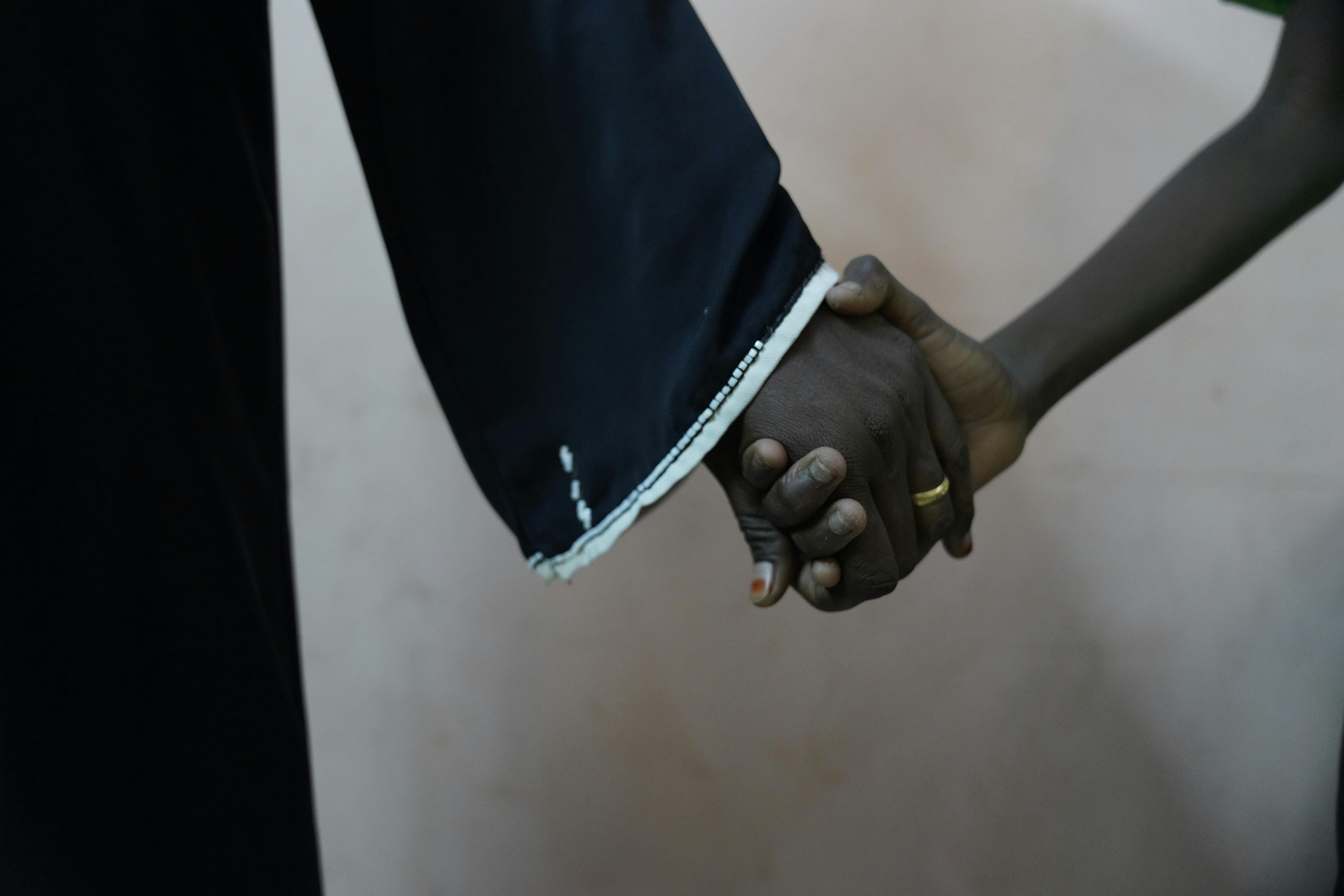 Sudan: Musa*, 11 anni, tiene stretta la mano di sua madre dopo la visita dallo psicologo e dall'assistente sociale che lo stanno aiutando ad affrontare il trauma delle violenze subite