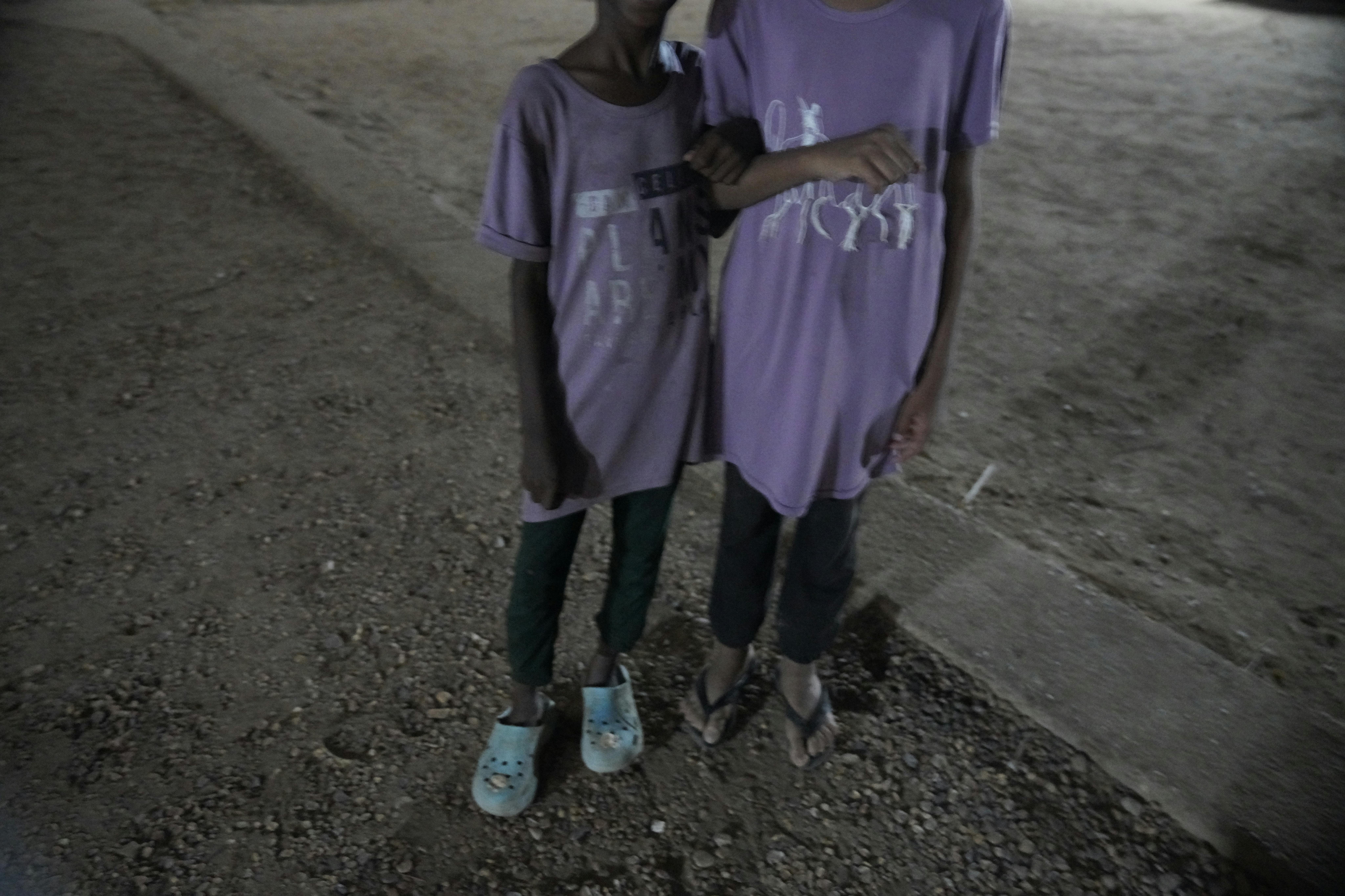 Queste due sorelle gemelle di otto anni si trovano fuori dal rifugio temporaneo, un'aula di scuola, dopo essere state costrette a fuggire dalla loro casa a causa del conflitto in Sudan. Un giorno, mentre raccoglievano l'acqua vicino all'aula, una delle ragazze è stata violentata da un uomo che viveva nella comunità.