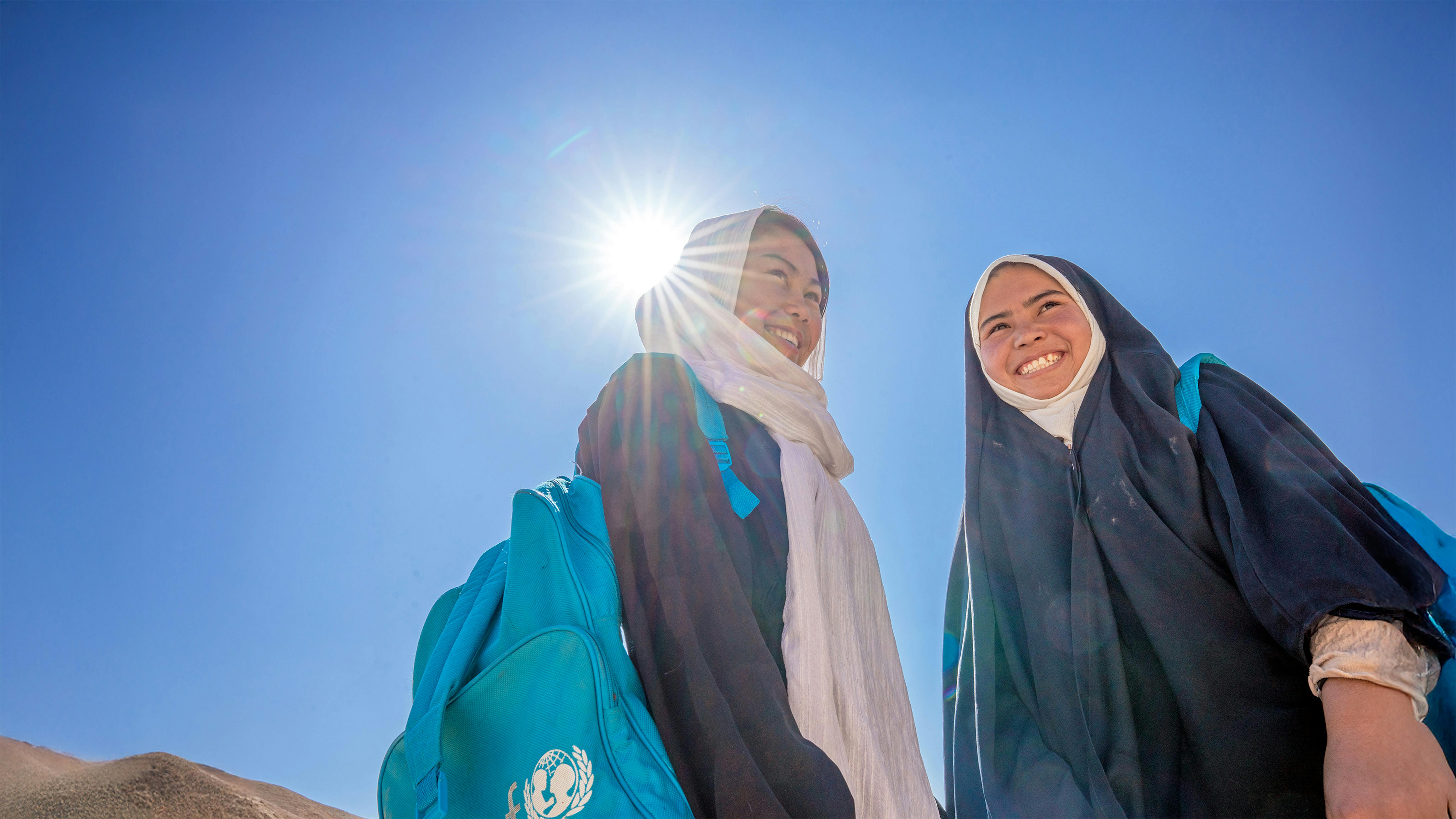 Sakina (a destra), 16 anni, si reca a piedi al Centro di apprendimento accelerato sostenuto dall'UNICEF nel villaggio di Surkhqul Payeen, nella provincia di Bamiyan, nell'Afghanistan centrale.