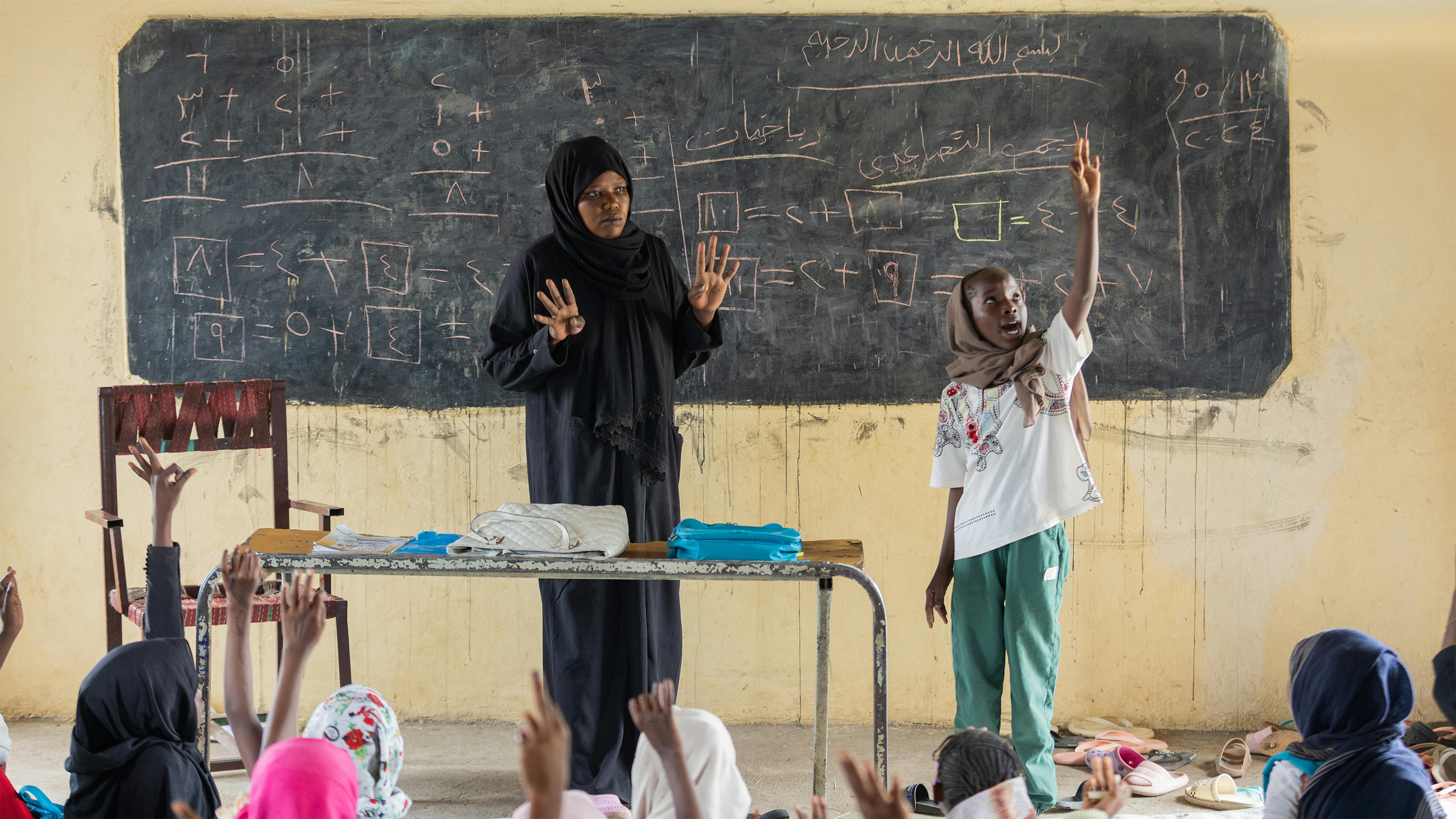In piedi davanti alla classe, nello spazio di apprendimento sicuro supportato dall'UNICEF nella scuola October North nello stato di Gedaref, in Sudan, Rabha, 11 anni, conta da uno a dieci in inglese mentre il resto della classe ripete dopo di lei, nell'aprile 2024.