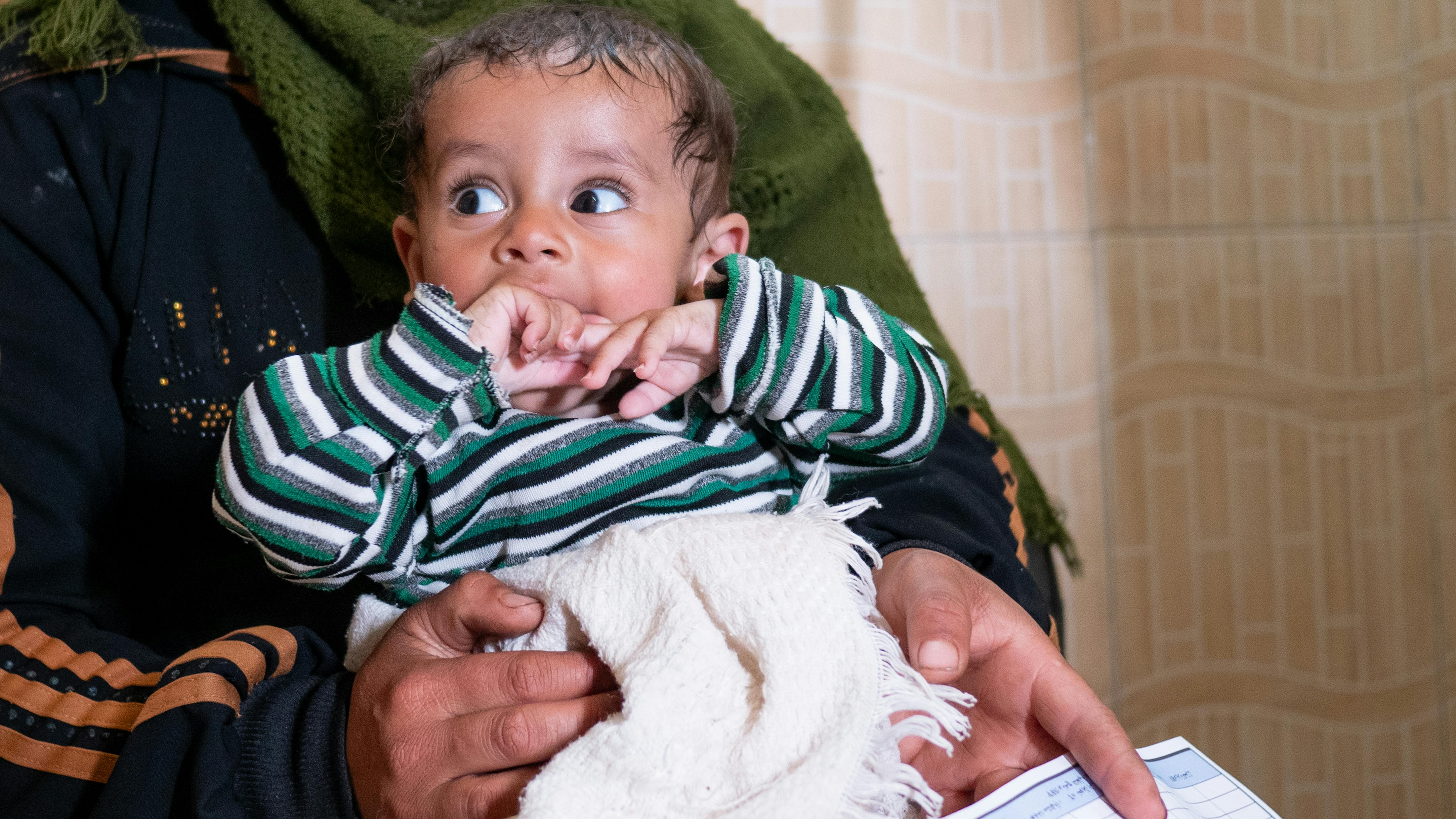 Siria - Ali, 7 mesi, tenuto in braccio dalla madre Hamda, in attesa del suo turno per essere sottoposto a screening in un centro sanitario e nutrizionale sostenuto dall'UNICEF nella città di Hama