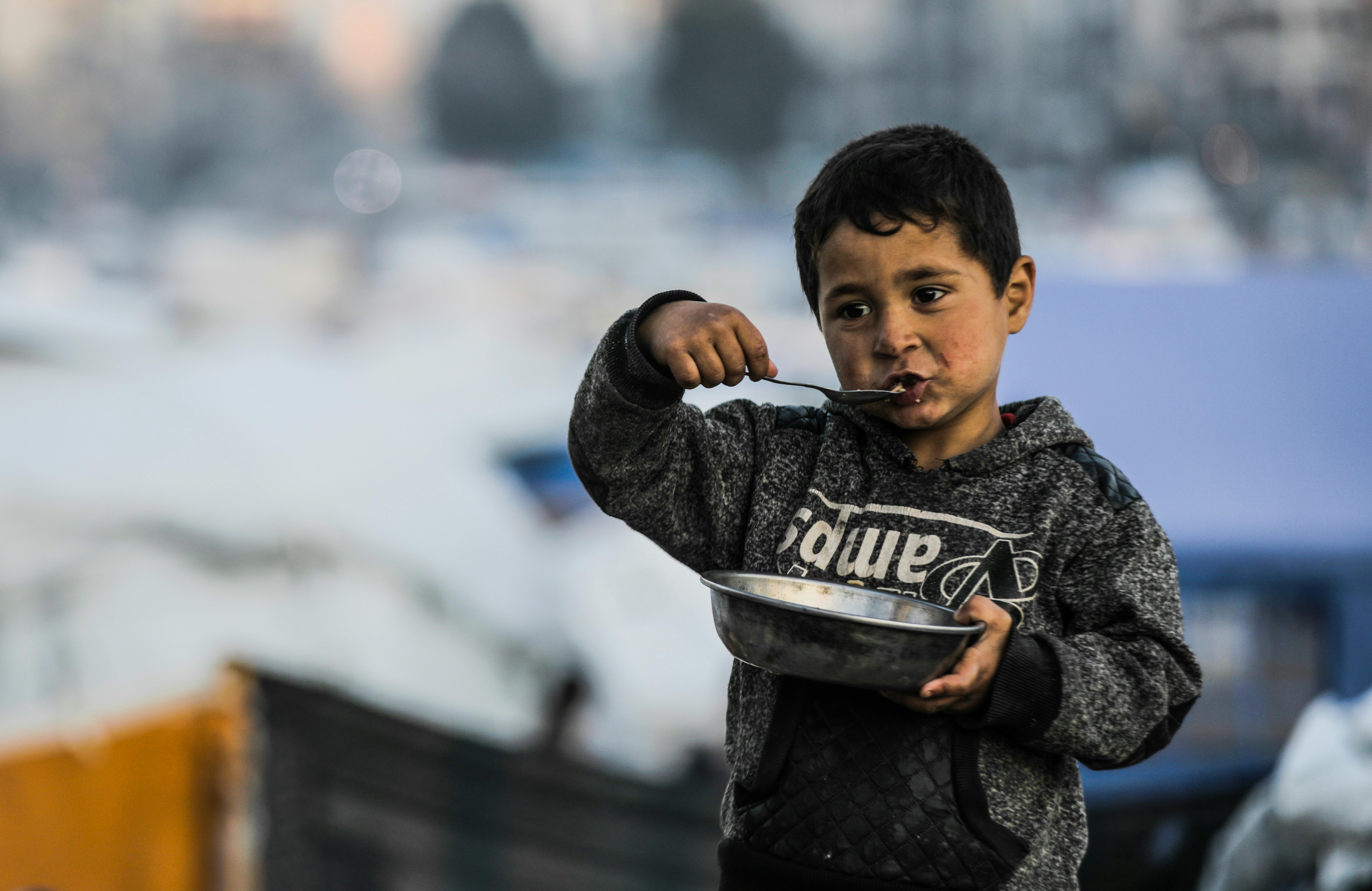 Gaza: Yusuf 5 anni, sta mangiando da una ciotola nel campo per sfollati in cui si è rifugiato con la sua famiglia dopo il cessate il fuoco. Possono contare solo sulle ciotole di riso che ricevono dalle organizzazioni umanitarie