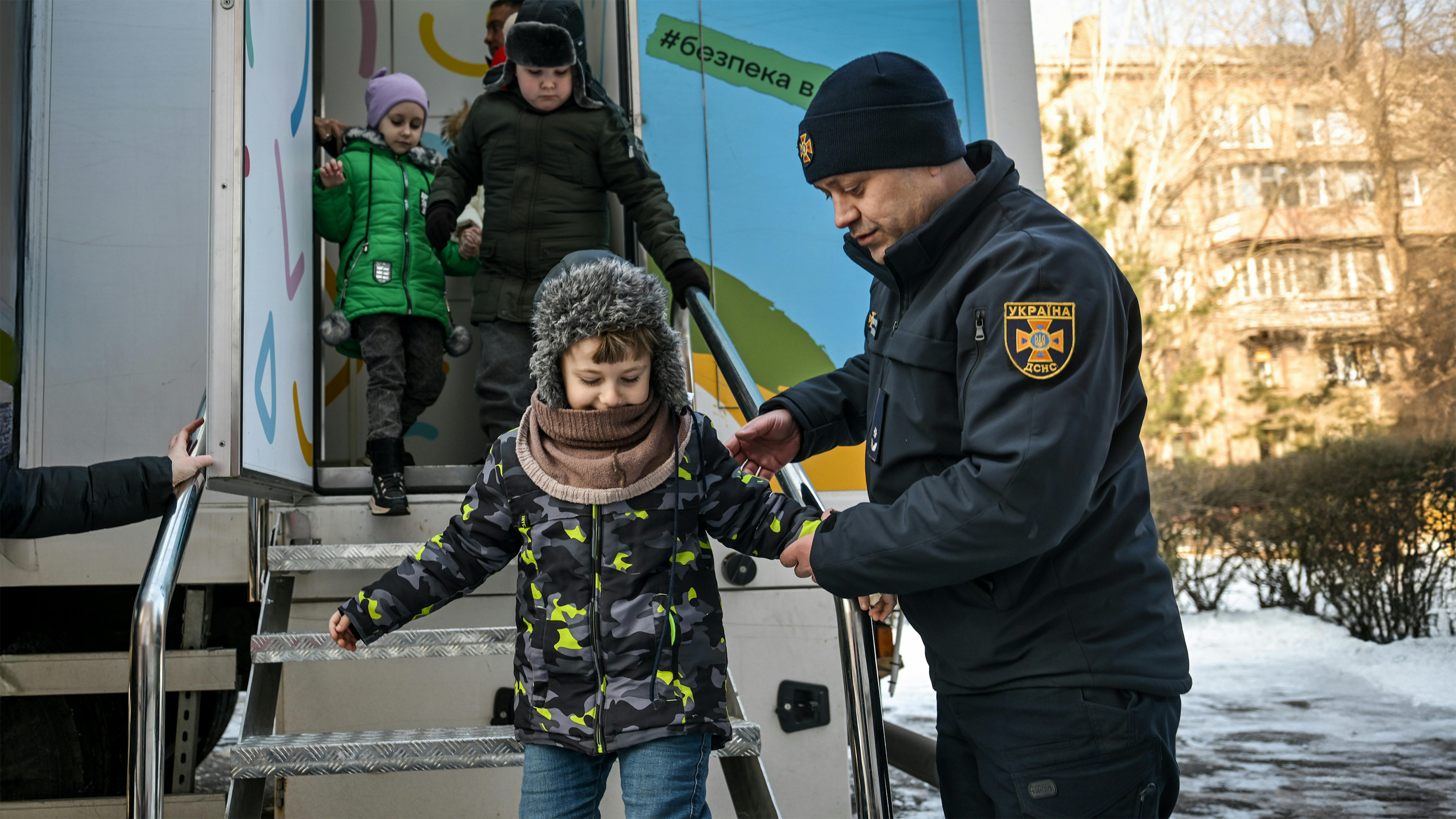 Ucraina -  Un ufficiale del Servizio di emergenza statale dell'Ucraina aiuta gli alunni della prima elementare a evacuare un'aula mobile di sicurezza dopo che una sirena antiaerea ha interrotto la lezione.
