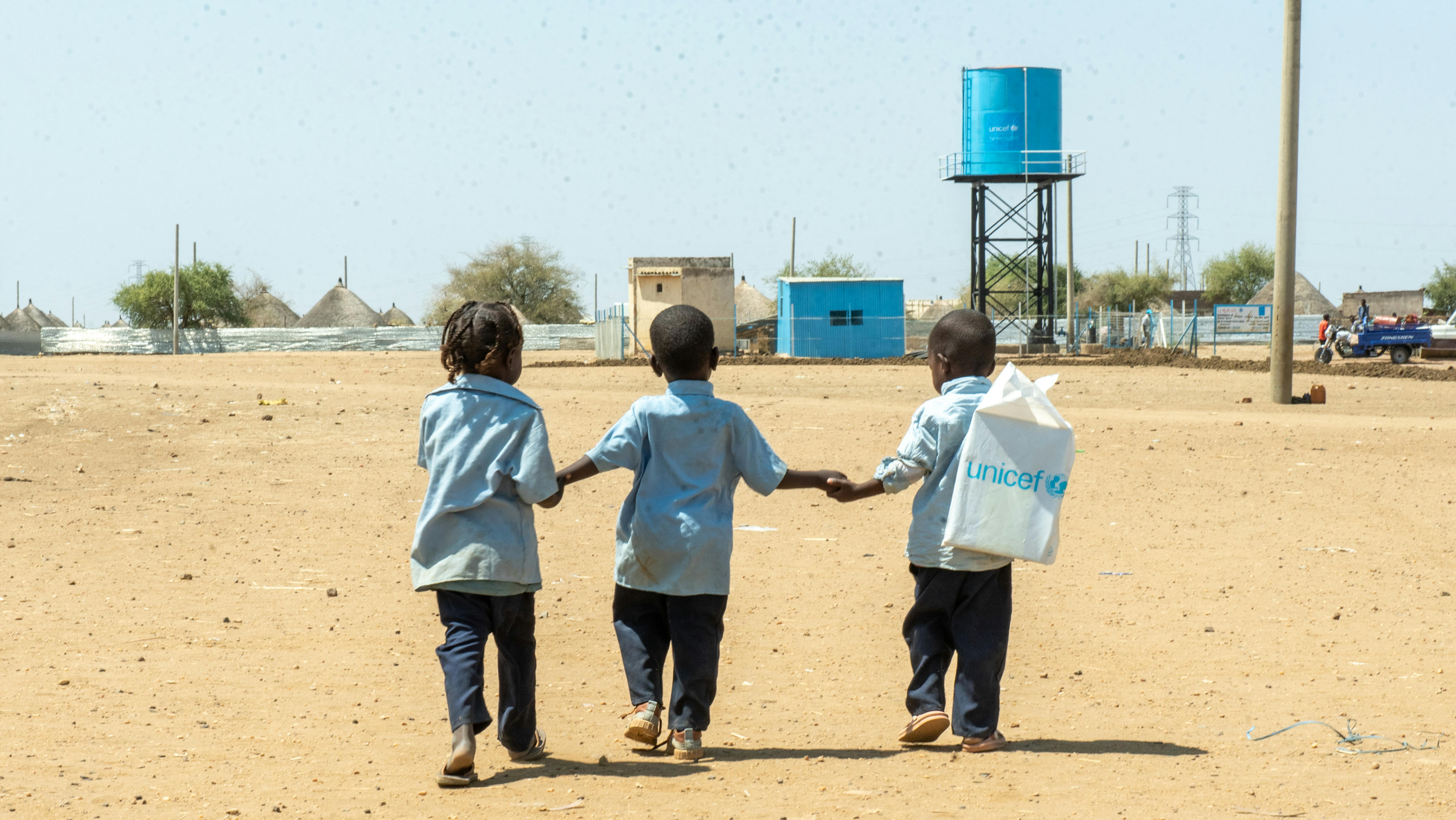 Sudan - Tre bambini tornano a casa a piedi da uno spazio a misura di bambino supportato dall'UNICEF nel campo per sfollati interni (IDP) di Al Houri, nello stato di Gedaref.