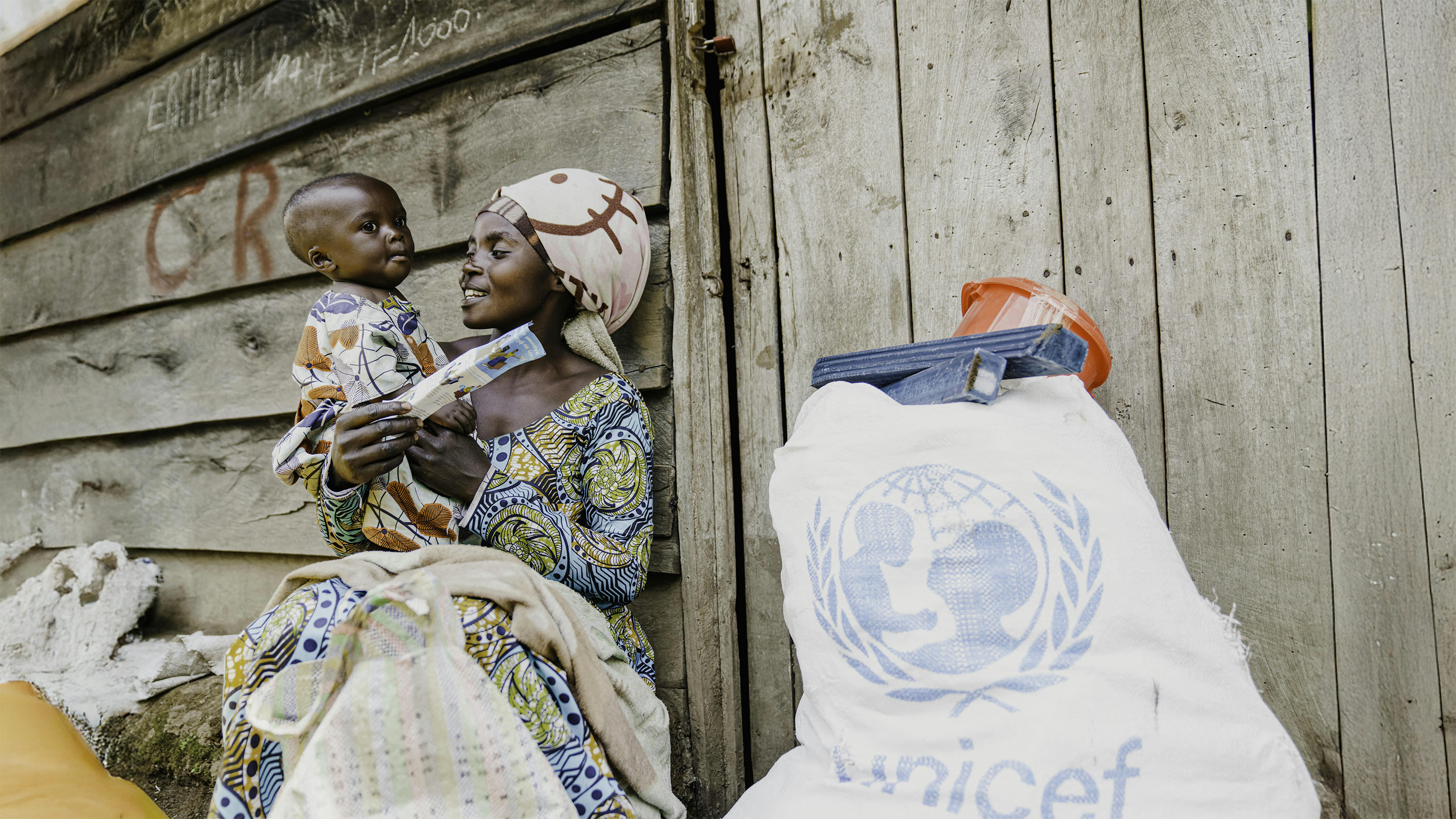 RD Congo - Judith, madre di tre figli, siede davanti al suo rifugio con il suo bambino dopo aver ricevuto articoli essenziali per la casa nel sito di distribuzione a Rugari, nel territorio di Rutshuru, nella provincia del Nord Kivu