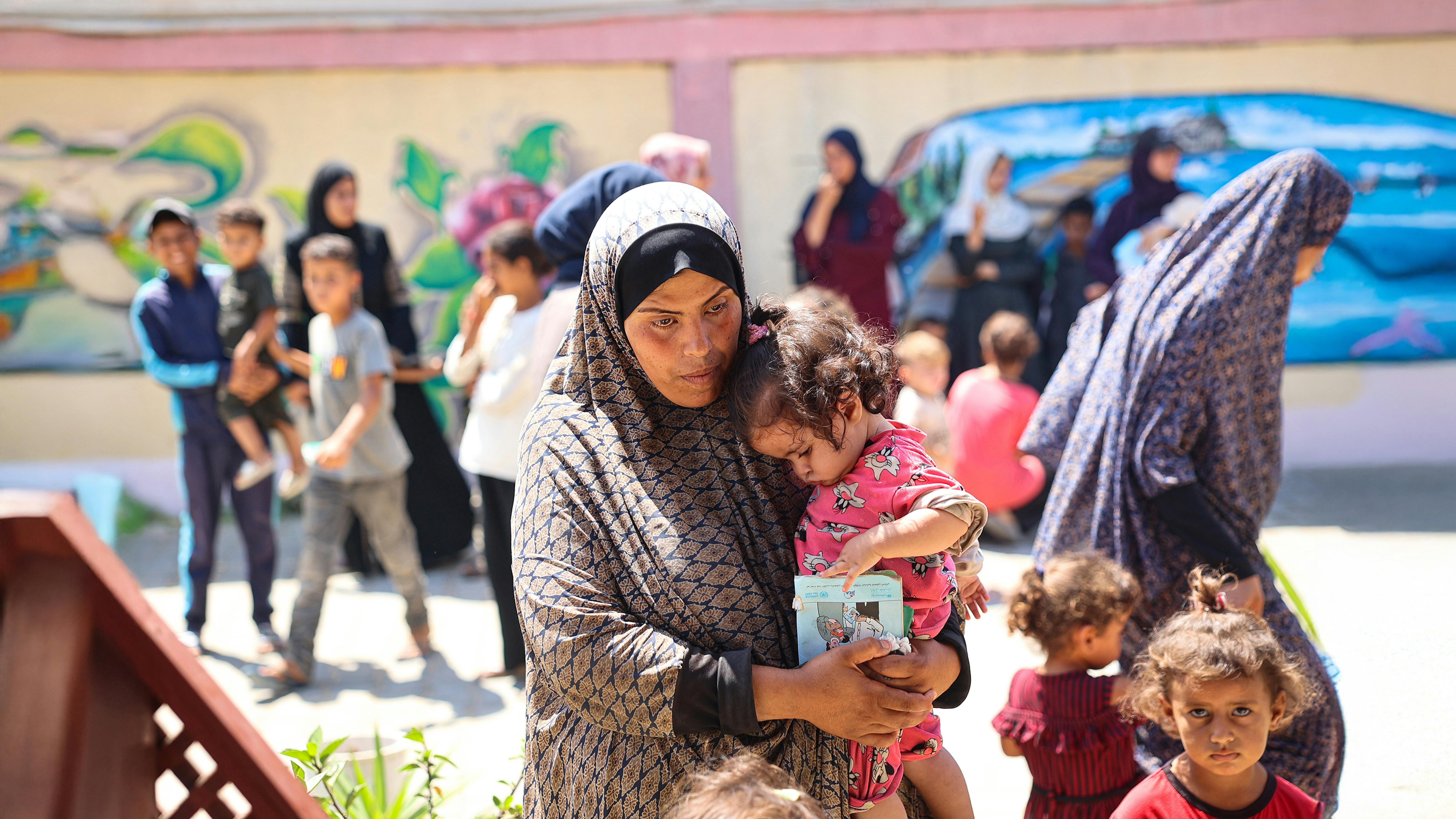 Safa con sua figlia Jana di un anno, mentre le viene misurata la circonferenza del braccio superiore medio (MUAC) e riceve una formula pronta all'uso come parte dello screening per la malnutrizione presso una clinica pediatrica sostenuta dall'UNICEF a Deir al-Balah, nella Striscia di Gaza.