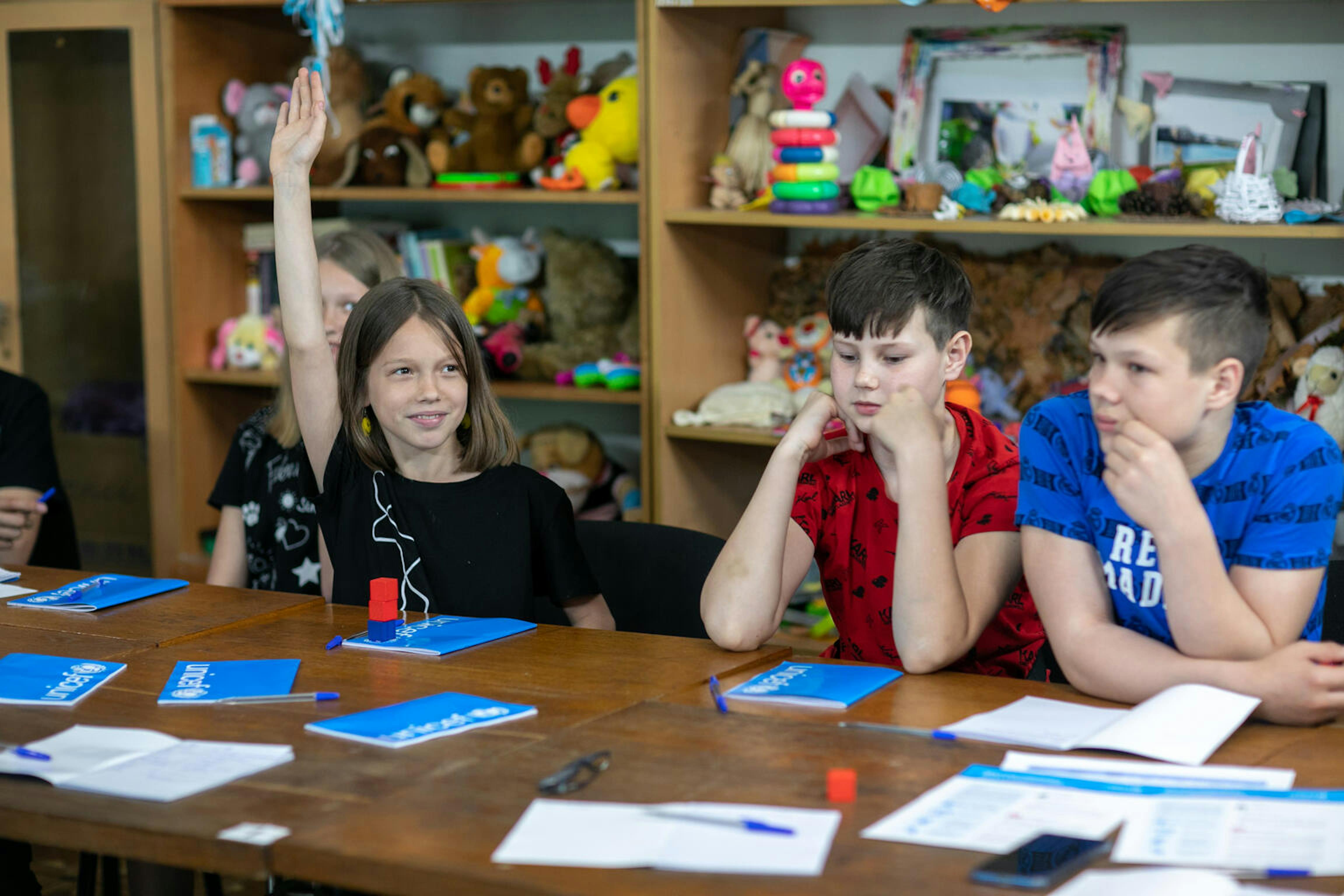 Bambini intorno ad una scrivania, con materiale scolastico UNICEF