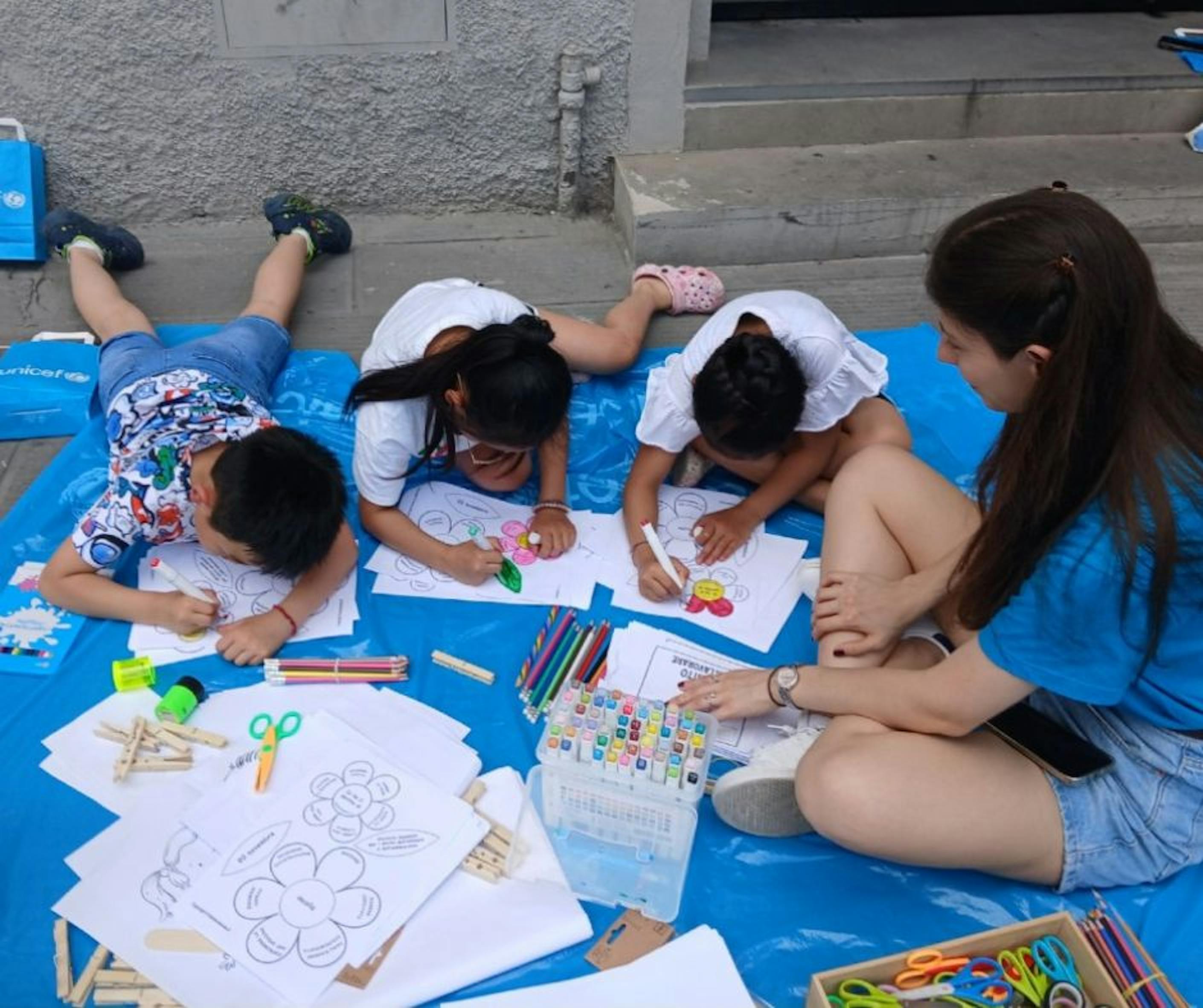 A Firenze, un gruppo di bambini disegna insieme ad una volontaria UNICEF durante le giornate dedicate al Diritto al Gioco