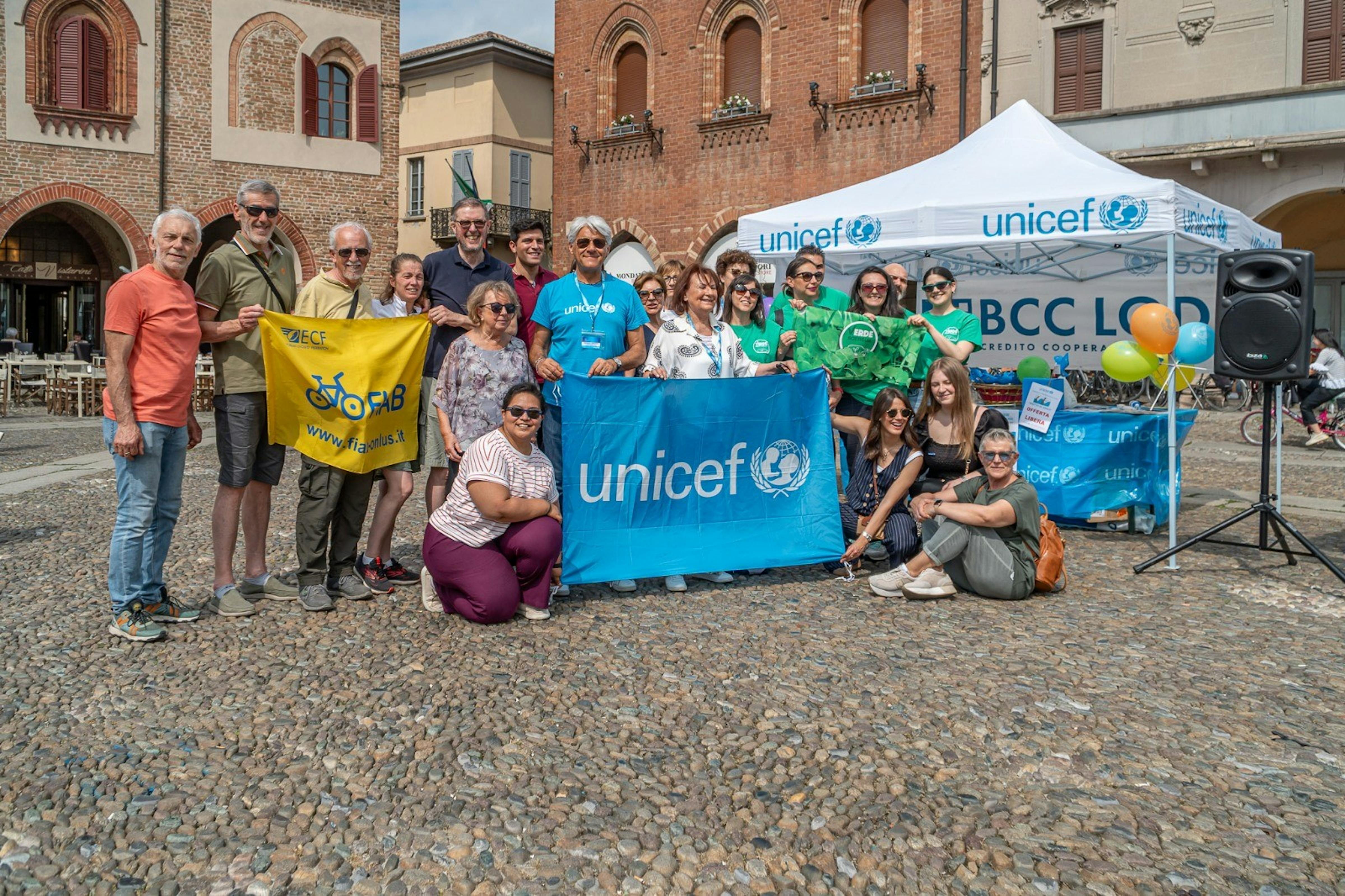 Lodi, i volontari sorridono accanto allo stand dell'UNICEF in cui si è svolta la giornata dedicata al gioco