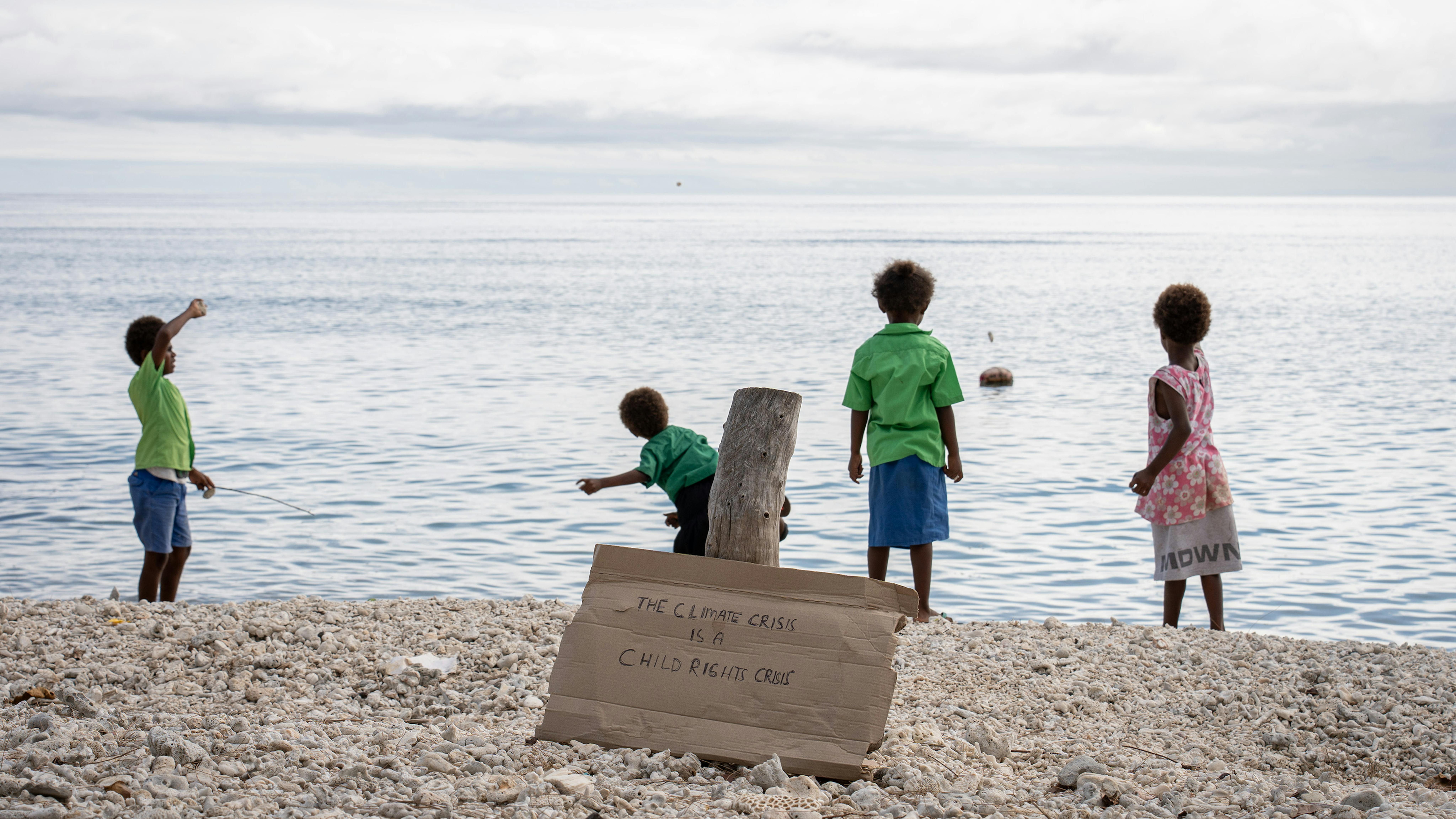 studenti della scuola elementare Utanlangi di Nguna che lanciano sassi in mare con la dichiarazione della crisi climatica che sta colpendo la loro casa.