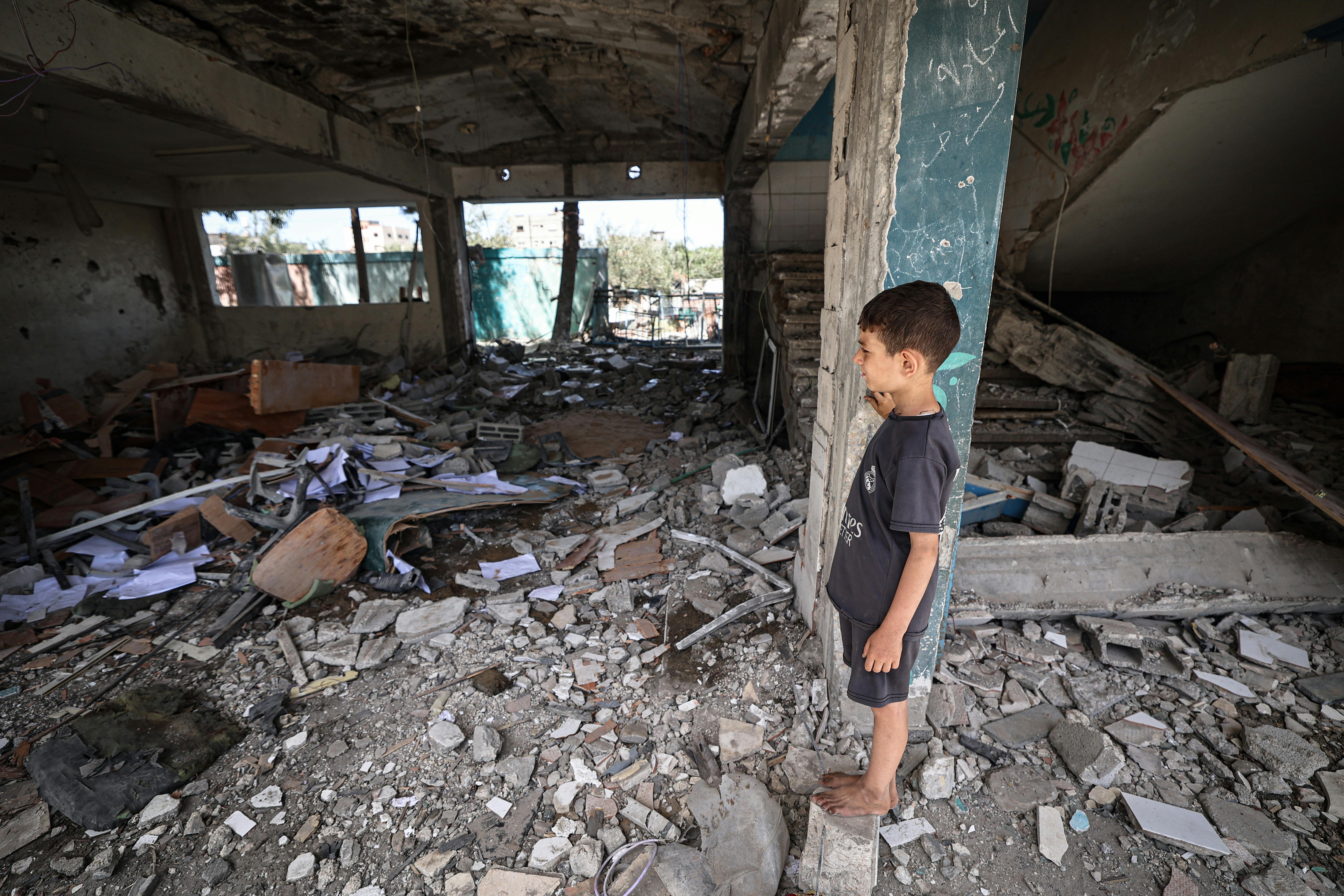 Un bambino palestinese osserva le macerie all'interno di un'aula di una scuola dell'UNRWA che ospita gli sfollati, colpita direttamente durante un attacco aereo sul campo di Nuseirat