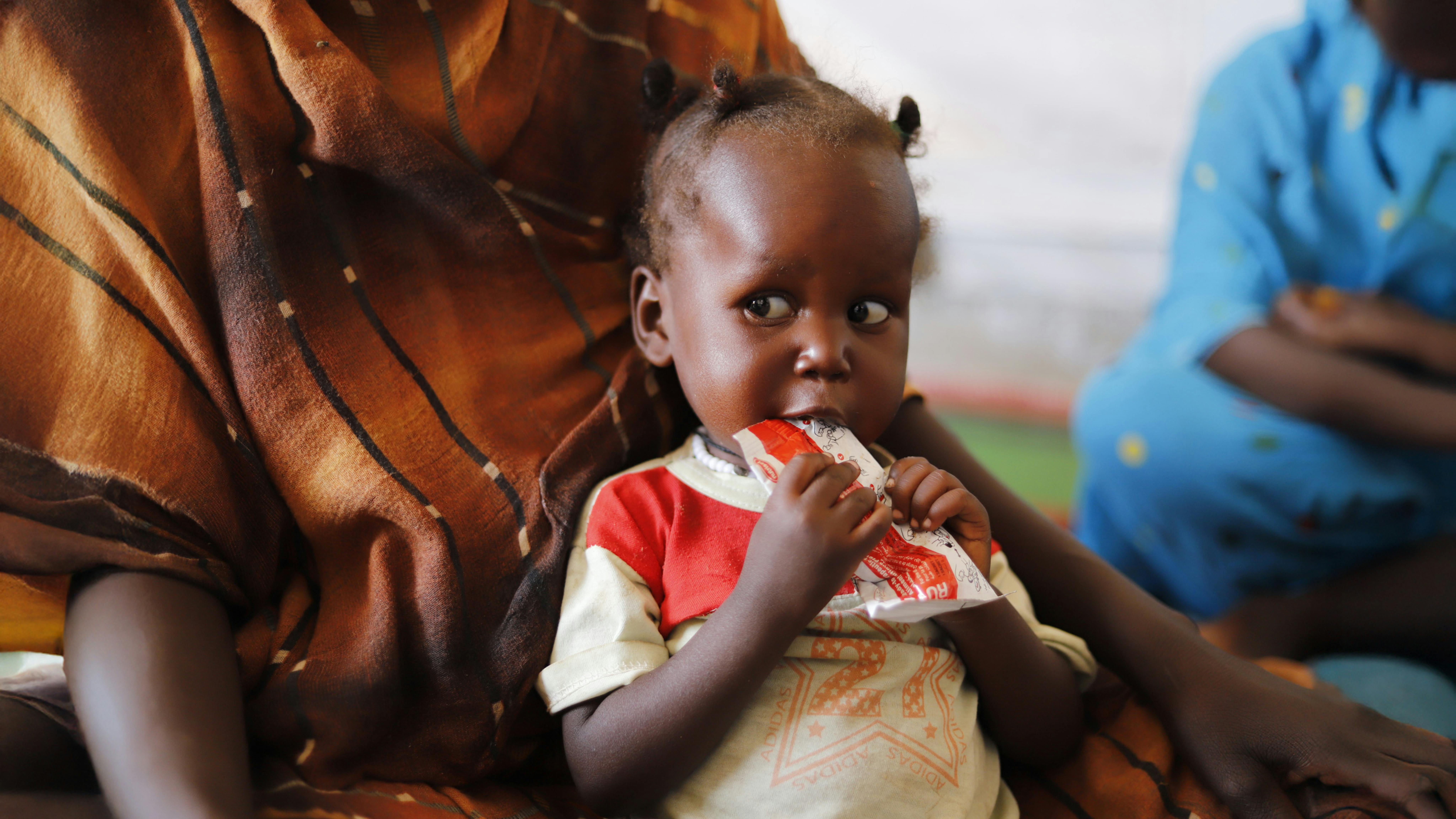 un bambino che soffre di malnutrizione mangia cibo terapeutico pronto all'uso in una clinica di salute primaria supportata dall'UNICEF a Tawila, nel Nord Darfur