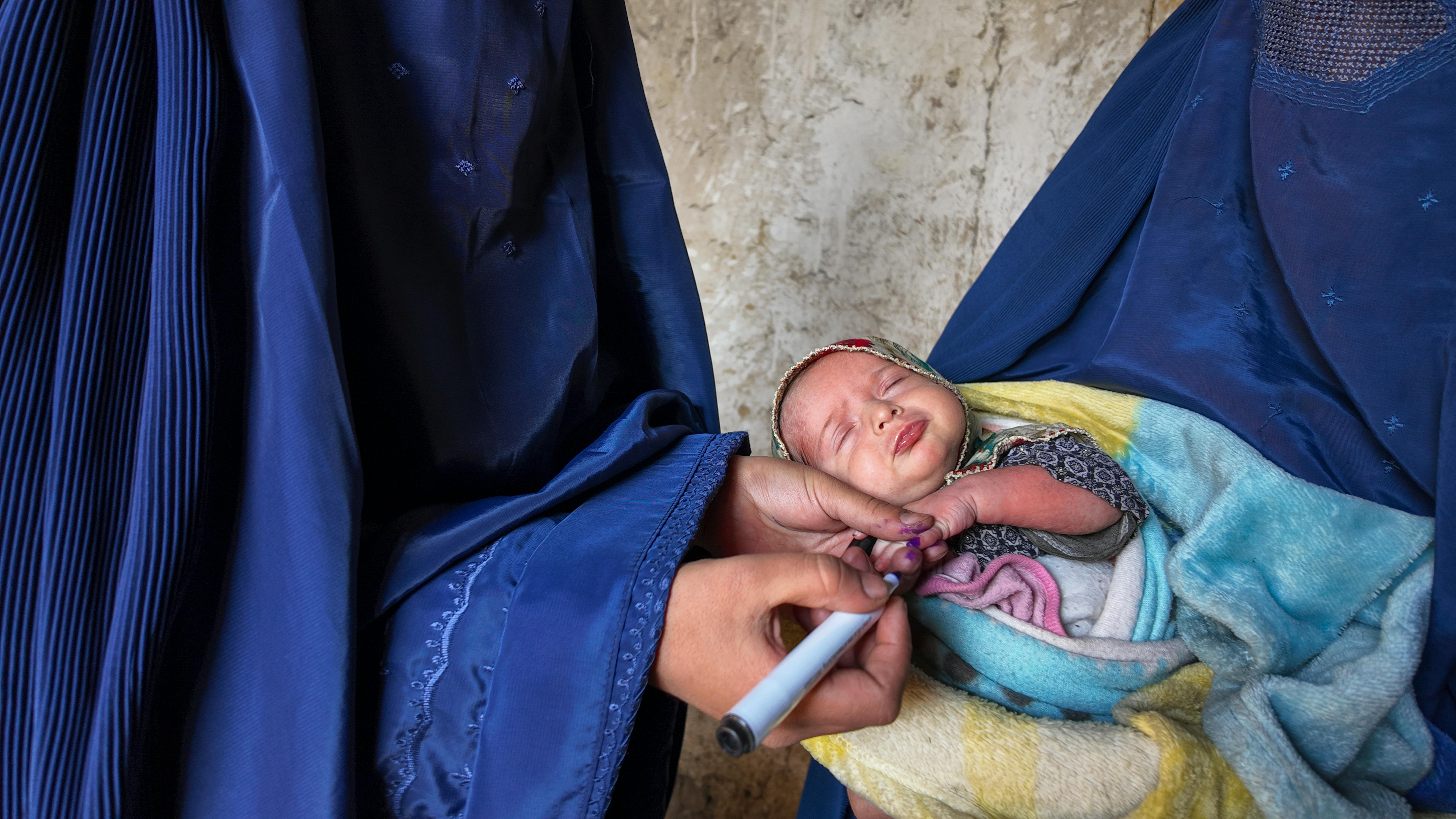 Bibi Hawa, vaccinatrice, che segna il dito del bambino, nel villaggio di Abrot, distretto di Bargimatal, provincia di Nuristan, Afghanistan