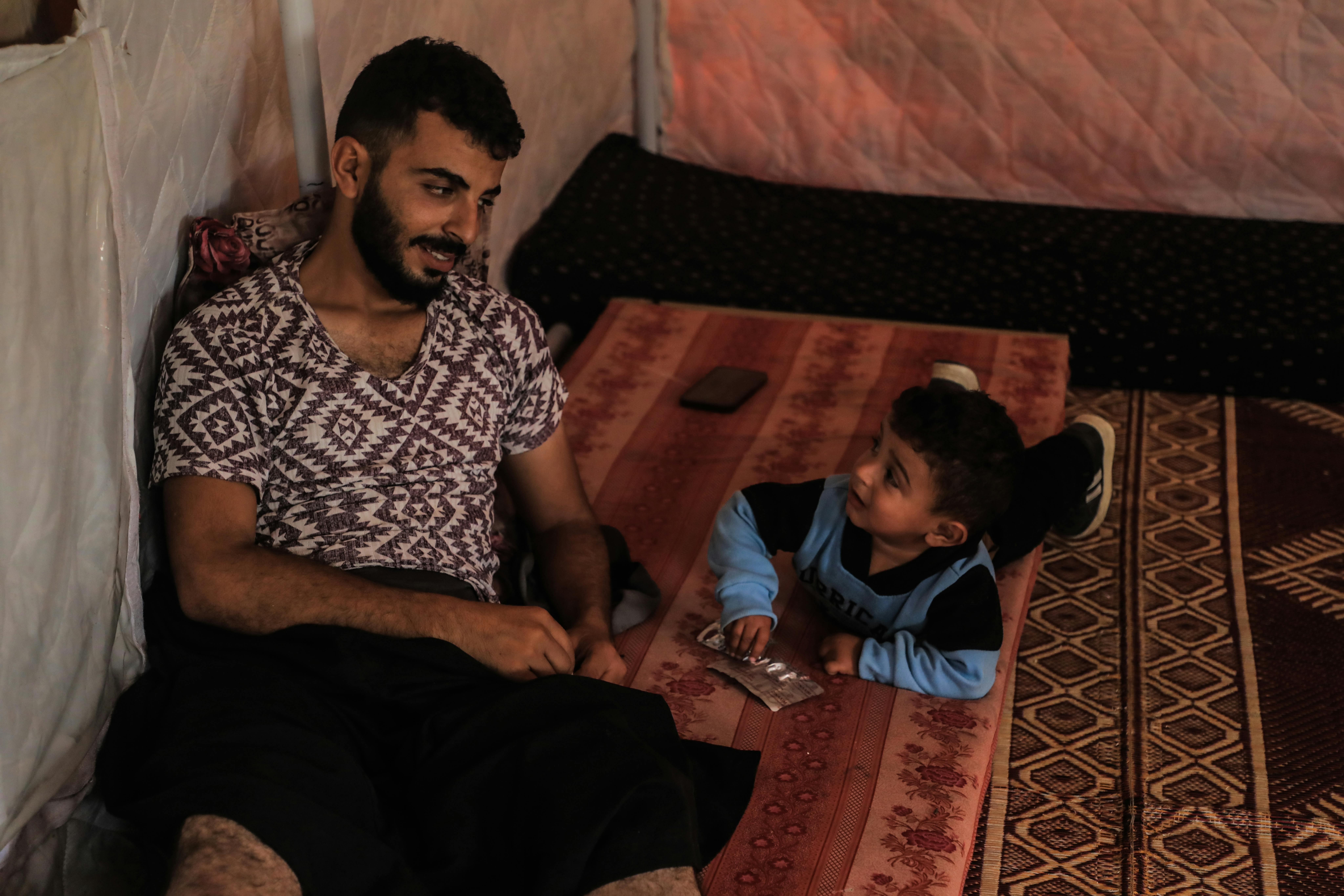 Masoud, soffre delle ferite riportate mentre si trovava in fila al centro di distribuzione. Qui si trova con uno dei suoi bambini, nella tenda in cui si è rifugiato insieme alla moglie