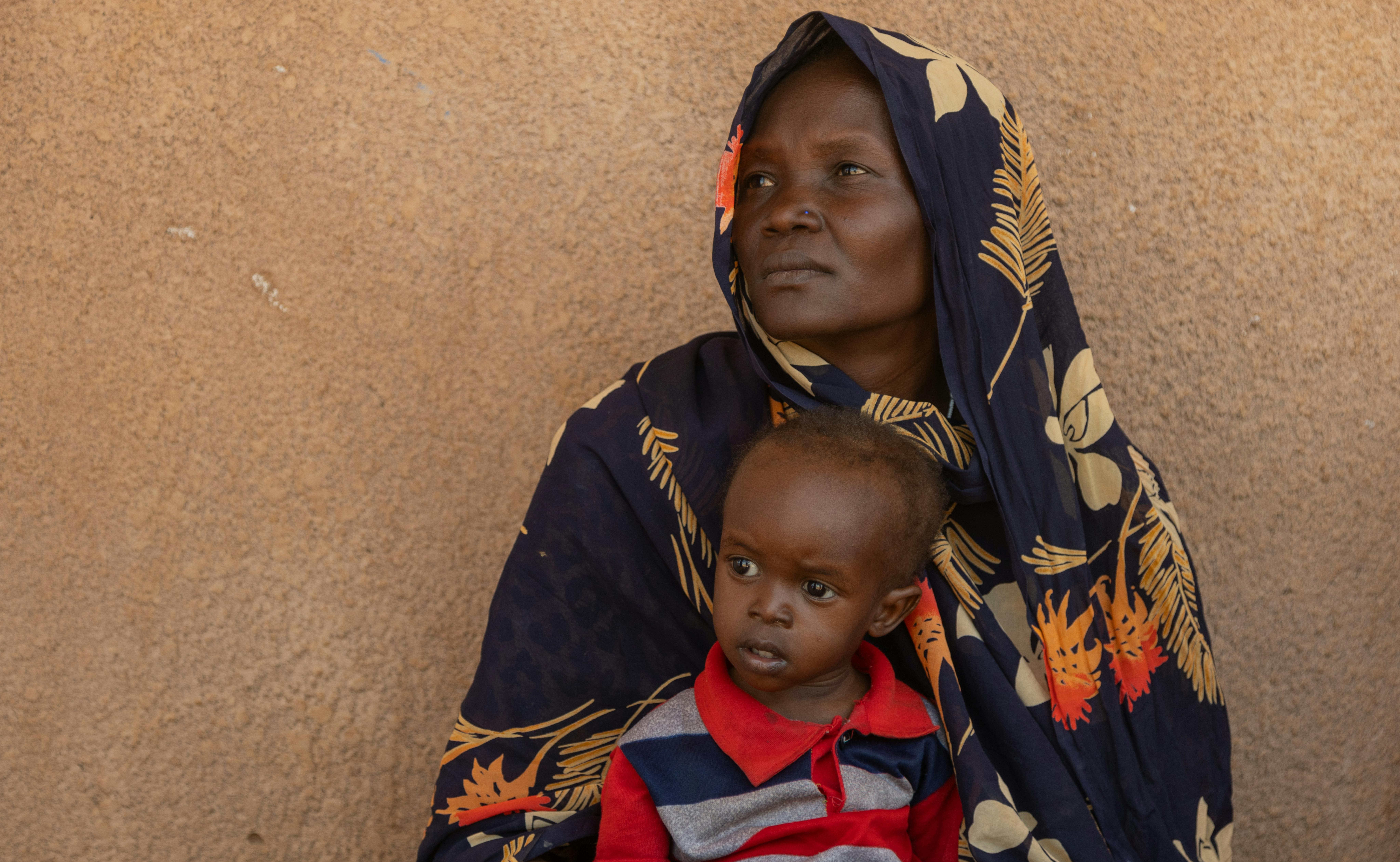 Sudan: una madre con il suo bambino in braccio sta seguendo una formazione sui rischi del colera e quali misure di prevenzione adottare. Gli incontri fanno parte di una serie di interventi messi in campo dall'UNICEF per migliorare le condizioni igienico sanitarie e sensibilizzare la popolazione sui rischi del colera