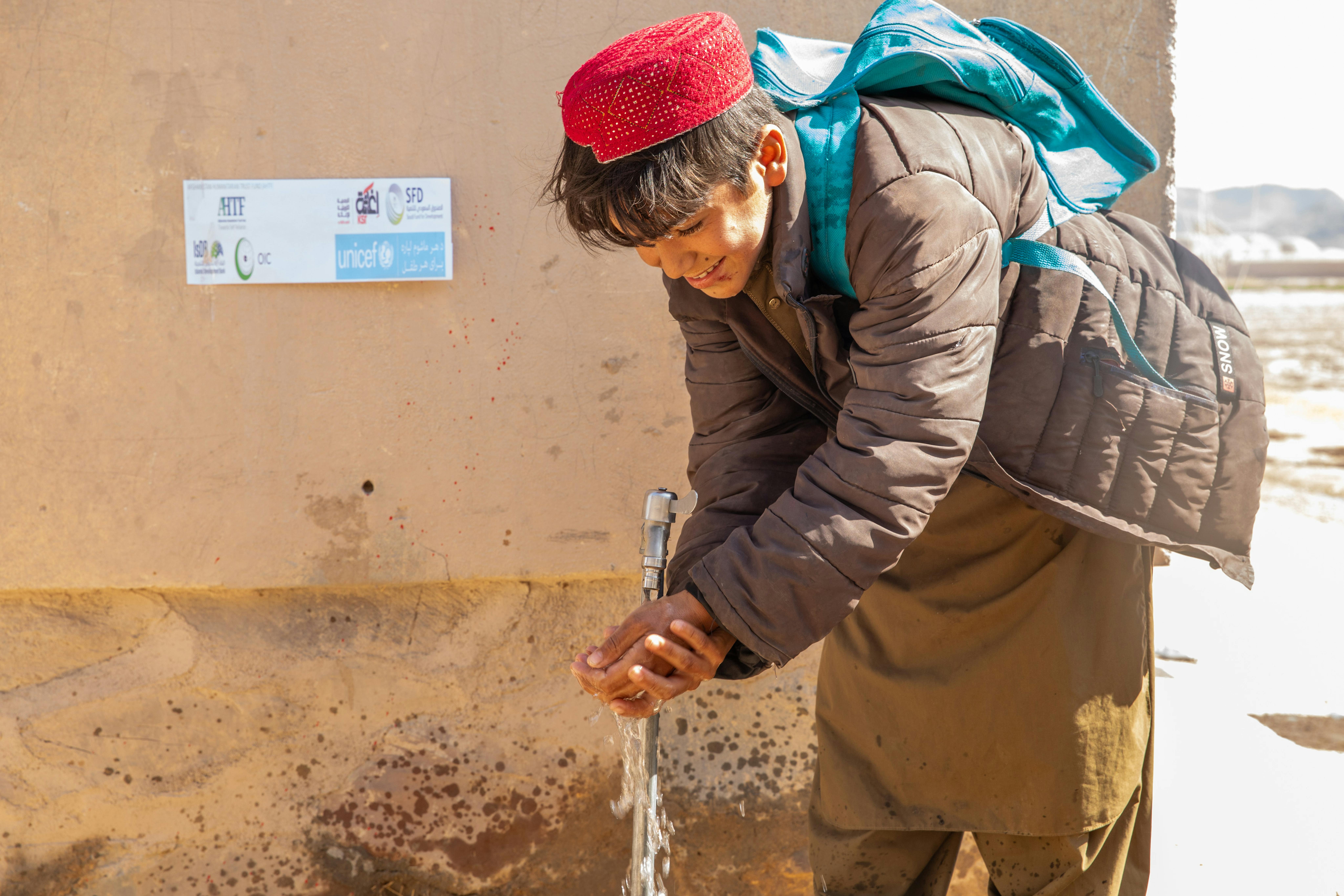 Masihullah, 13 anni, si lava le mani al nuovo rubinetto che porta acqua potabile pulita alla sua scuola, grazie al sistema idrico canalizzato recentemente inaugurato nel villaggio di Loy Kariz (Khormaloq), nel centro provinciale di Farah, Afghanistan