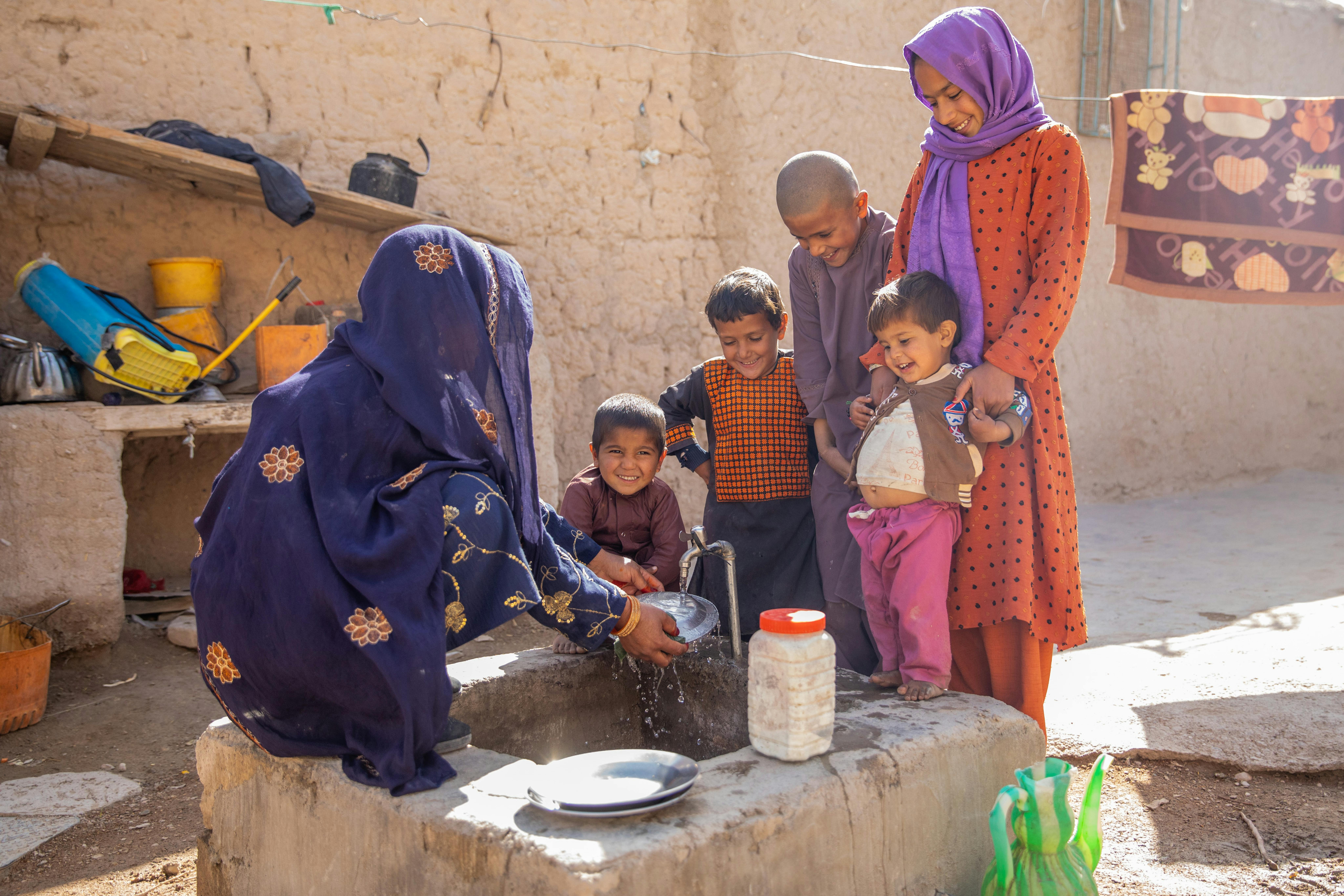 Amina, 48 anni, sta lavando i piatti nella fontanella davanti casa dove l'UNICEF ha portato acqua potabile grazie al nuovo sistema idrico ad energia solare. Siamo nel villaggio di Khormaloq, in Afghanistan.