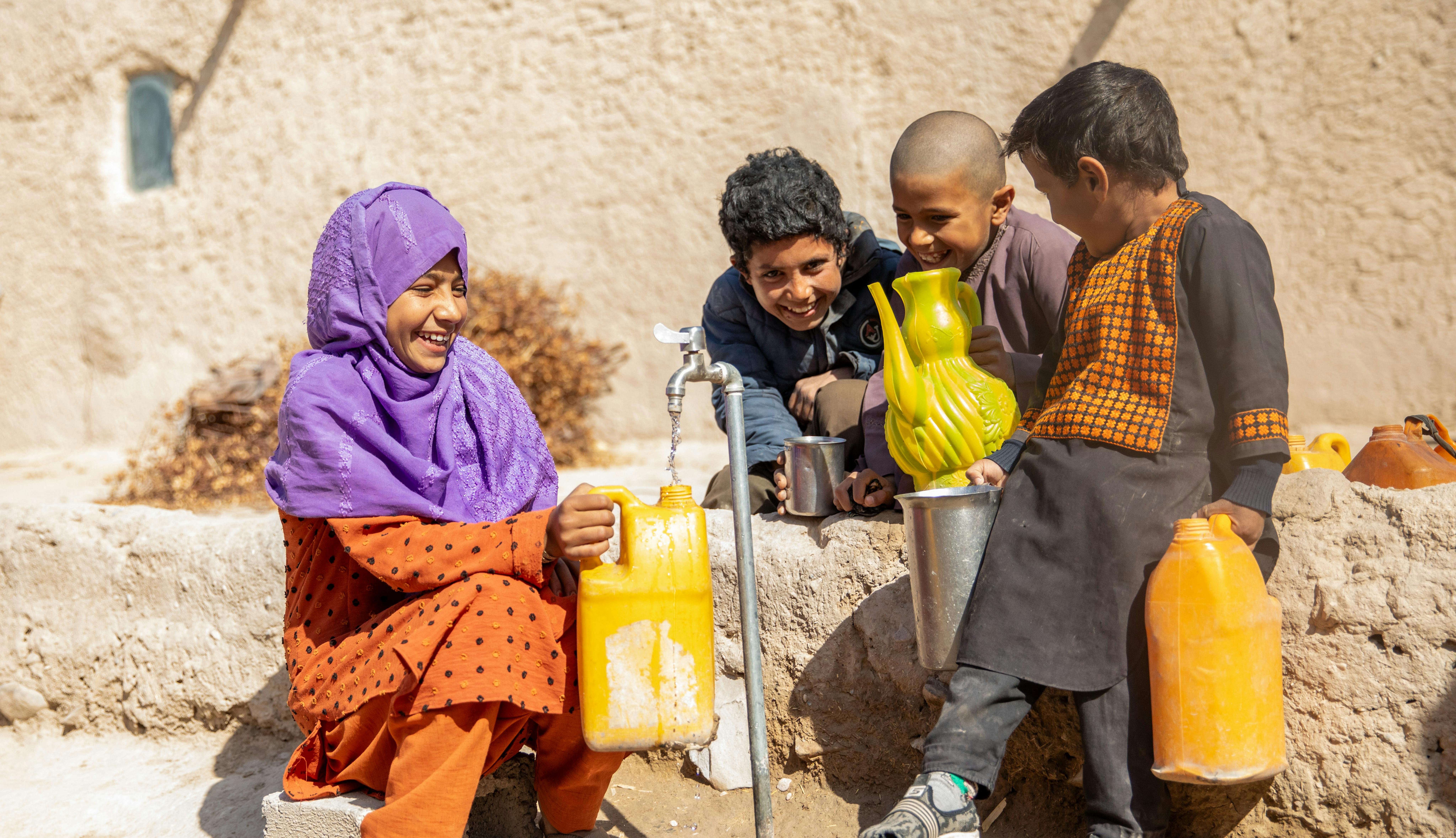 Rozia, 11 anni, insieme ad altri bambini sta riempiendo una tanica dal nuovo rubinetto che porta acqua potabile pulita direttamente nel villaggio, grazie al sistema idrico canalizzato recentemente inaugurato dall'UNICEF. Siamo in Afghanistan