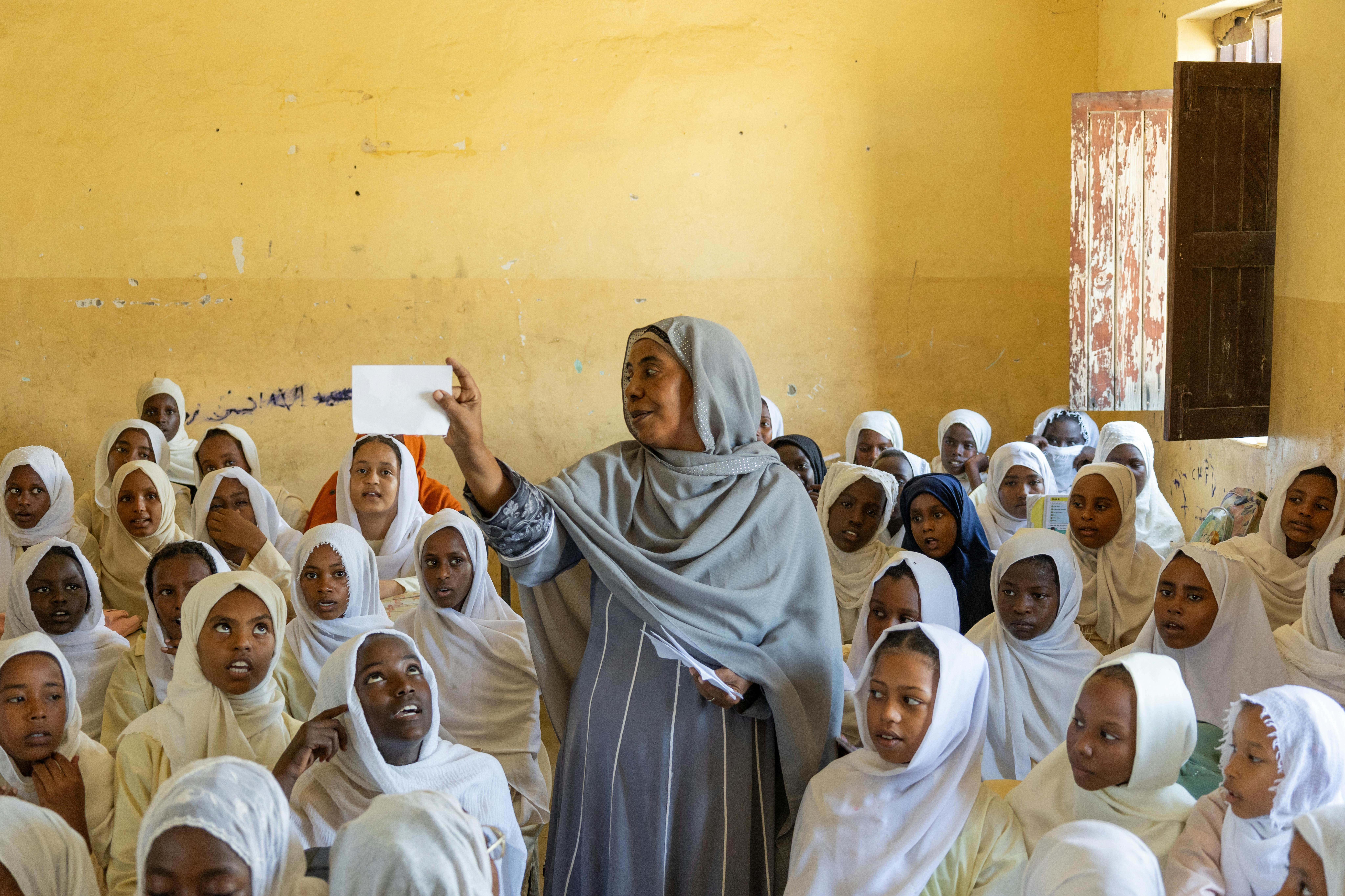 Sudan: gli alunni della scuola elementare Salalab Eastern di Port Sudan seguono una lezione con il supporto di Najat, un'insegnante volontaria che deve gestire classi sovraffollate a cause degli sfollamenti