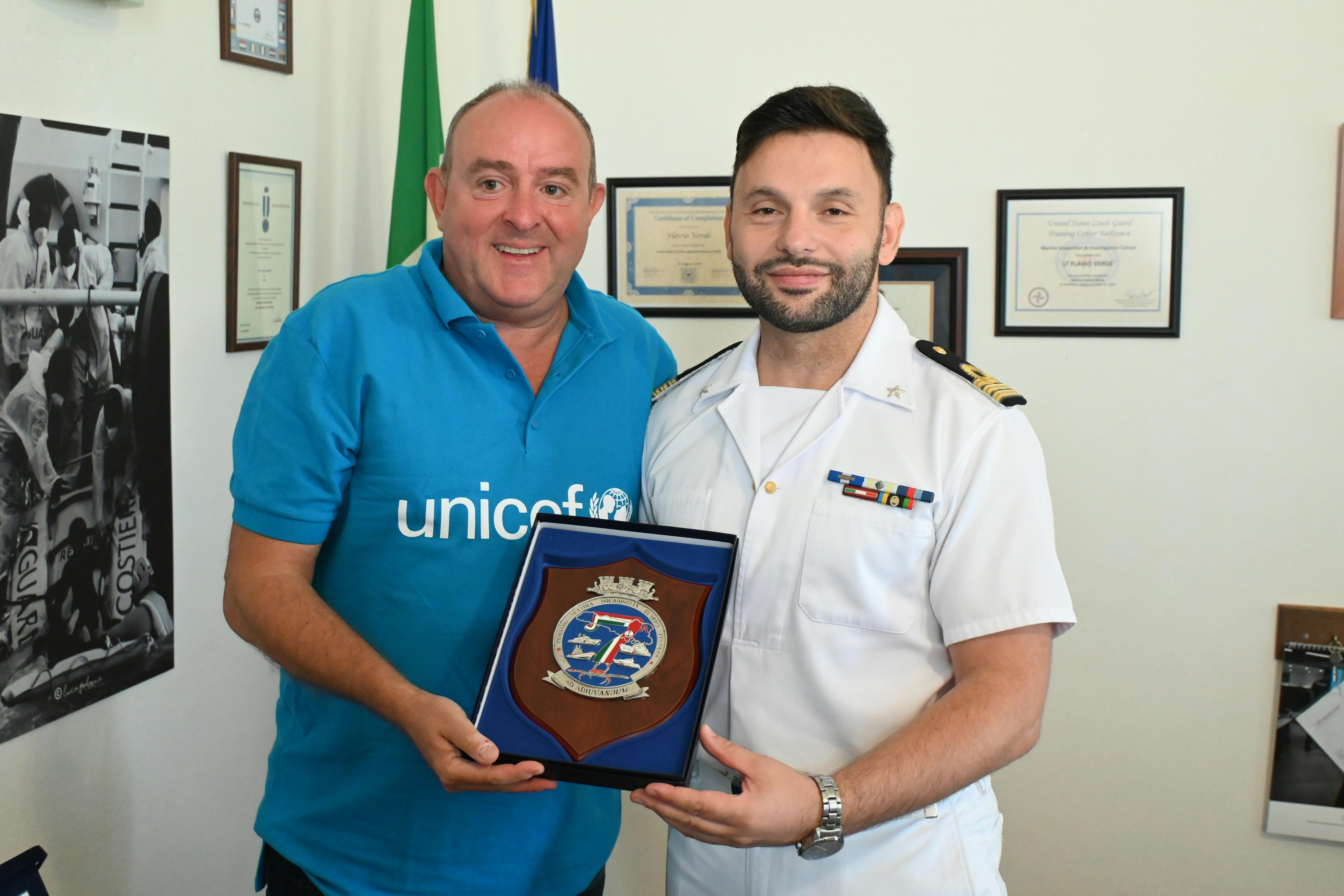 Nicola Graziano, Presidente dell'UNICEF Italia, riceve la targa dal tenente Flavio Verde della Guardia Costiera.