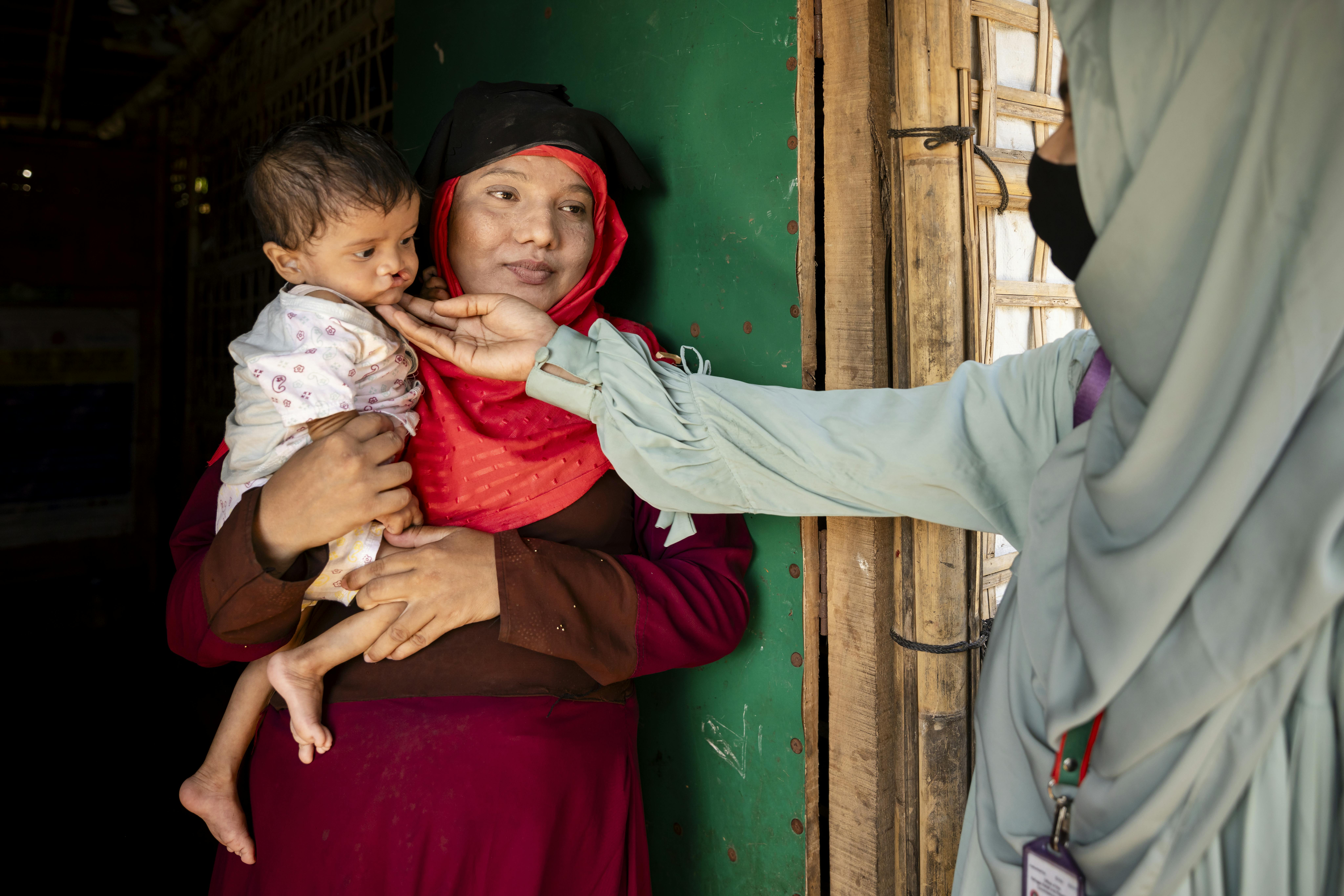 Taslima, volontaria nutrizionista della comunità Rohingya, visita Rashida, 25 anni, per fornire consulenza nutrizionale e valutare lo stato nutrizionale di sua figlia Noor di otto mesi nel loro rifugio nei campi profughi Rohingya a Cox's Bazar, in Bangladesh.