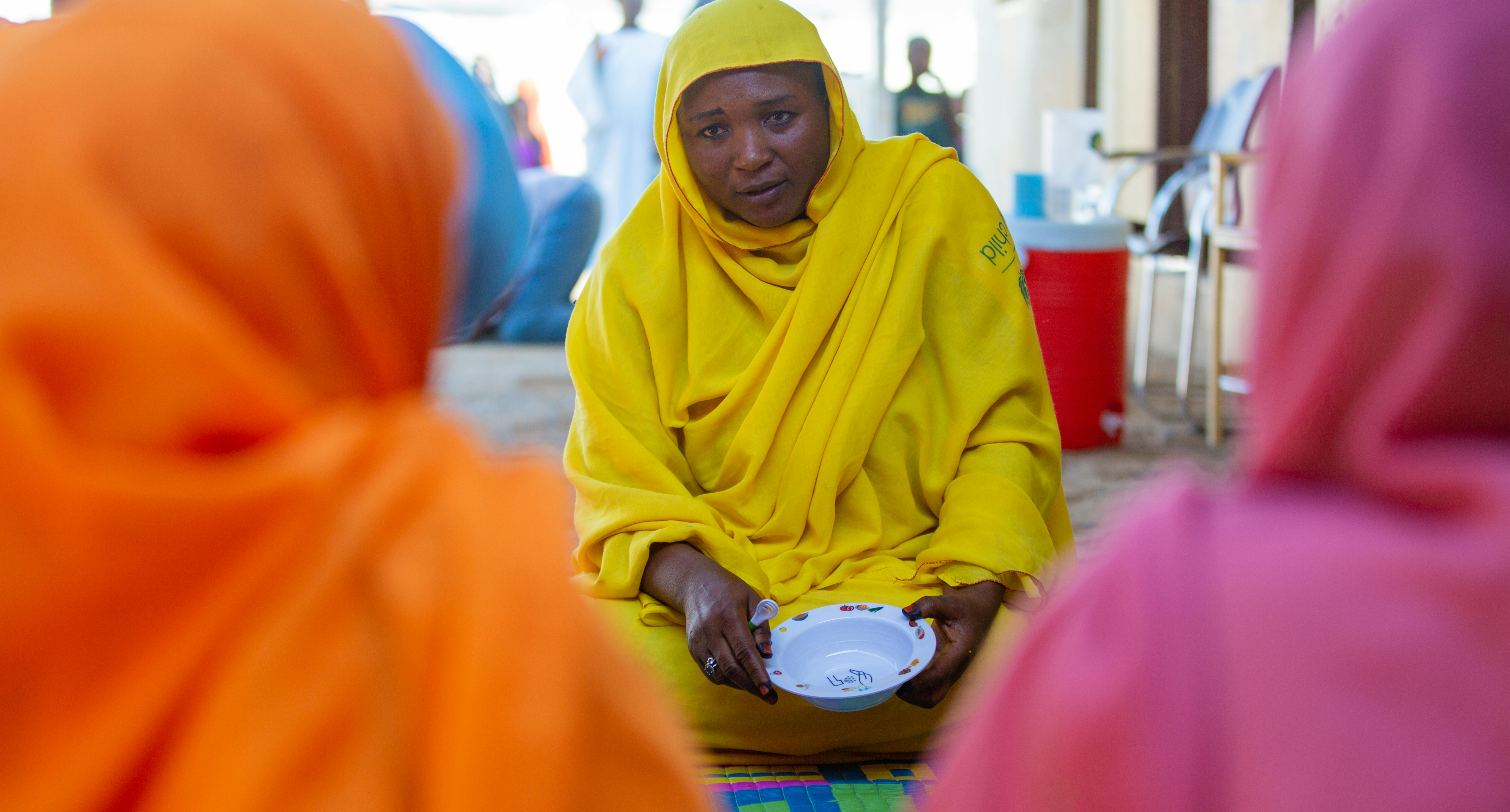 Muzdalifa, madre e membro del Gruppo di Supporto alle Madri formato dall'UNICEF, forma le donne sulle corrette pratiche di alimentazione dei bambini utilizzando una ciotola e un cucchiaio complementari - un'innovazione dell'UNICEF.