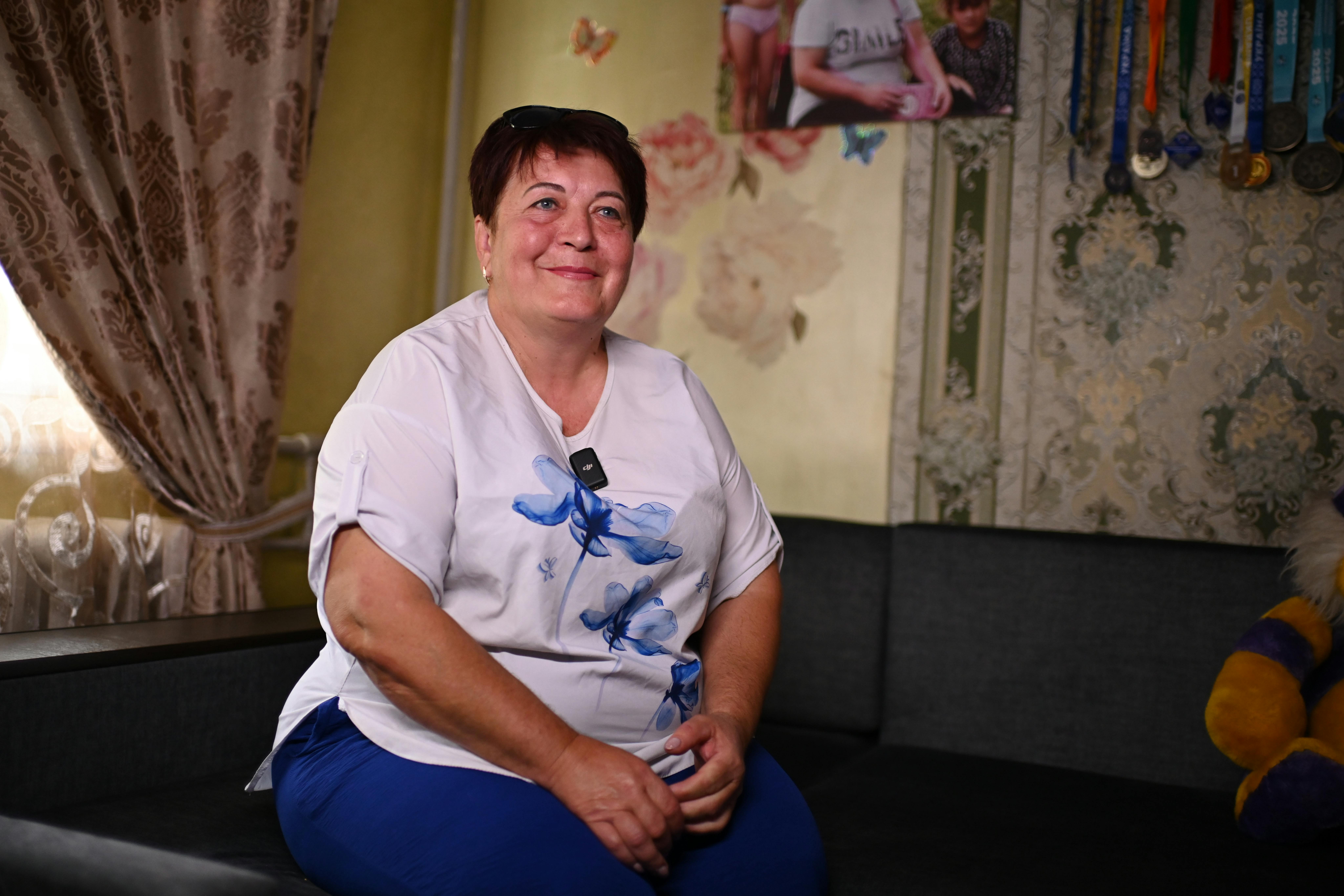 Ucraina: Nelya, fondatrice della prima casa famiglia a Znamenivka, sorride nel suo soggiorno, uno spazio pieno di calore, fotografie e medaglie guadagnate dai bambini che cresce.