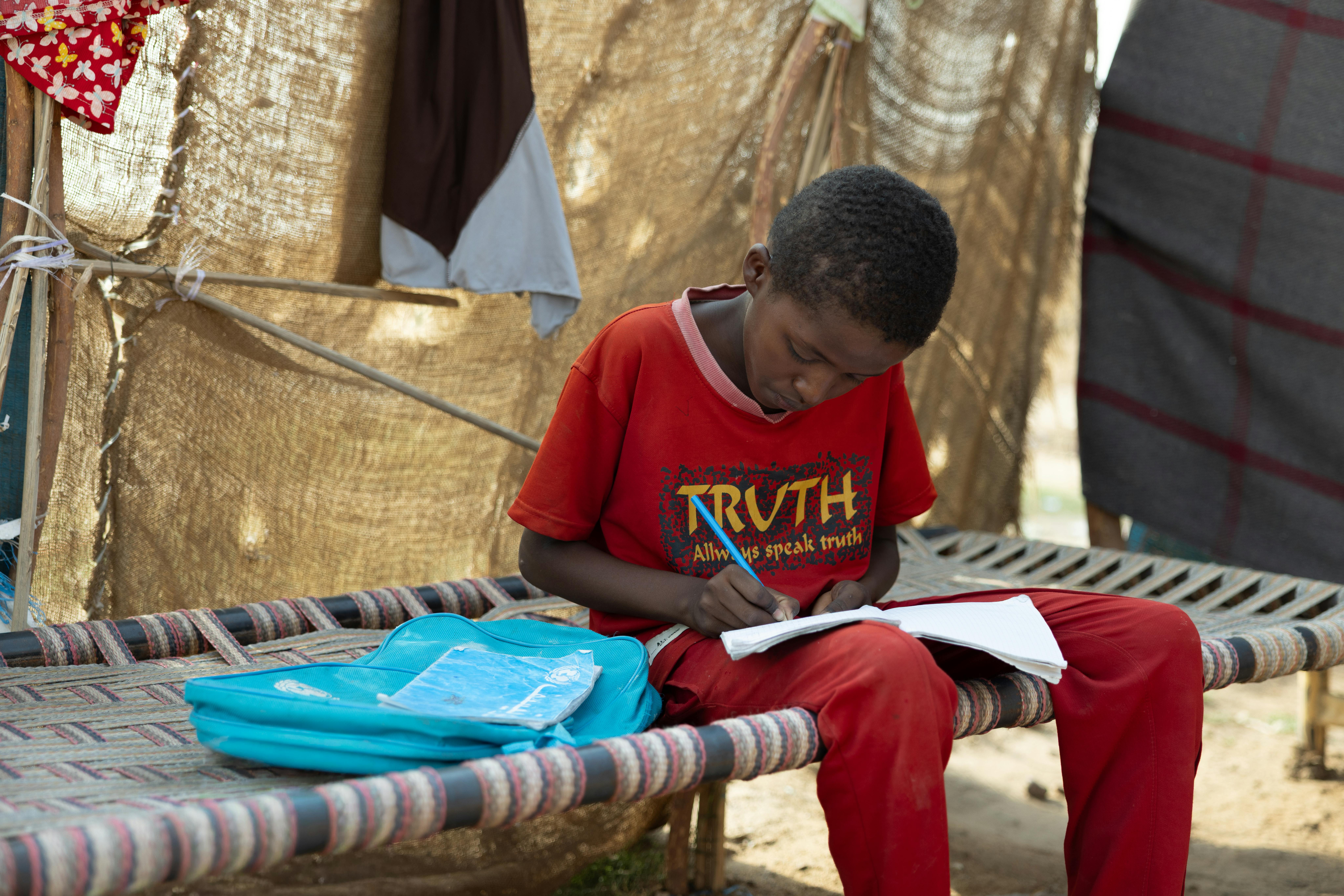 Azuz, 13 anni, fa i compiti nel rifugio per sfollati interni ad Atbara, nello stato del fiume Nilo, in Sudan