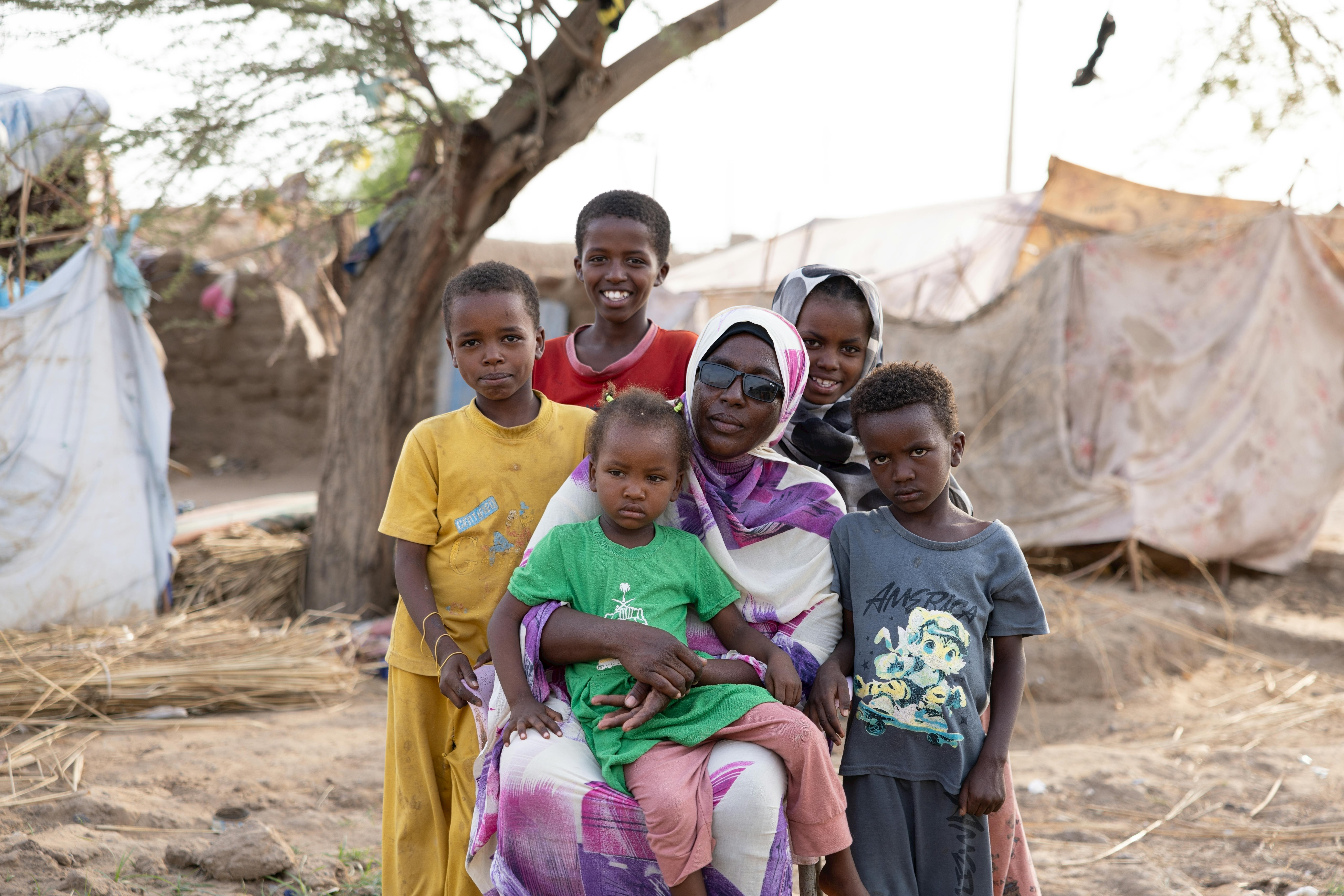 Azuz, 13 anni, e la sua famiglia sono davanti ad una delle tende che li ospitano nel campo per sfollati interni ad Atbara, nello stato del fiume Nilo.