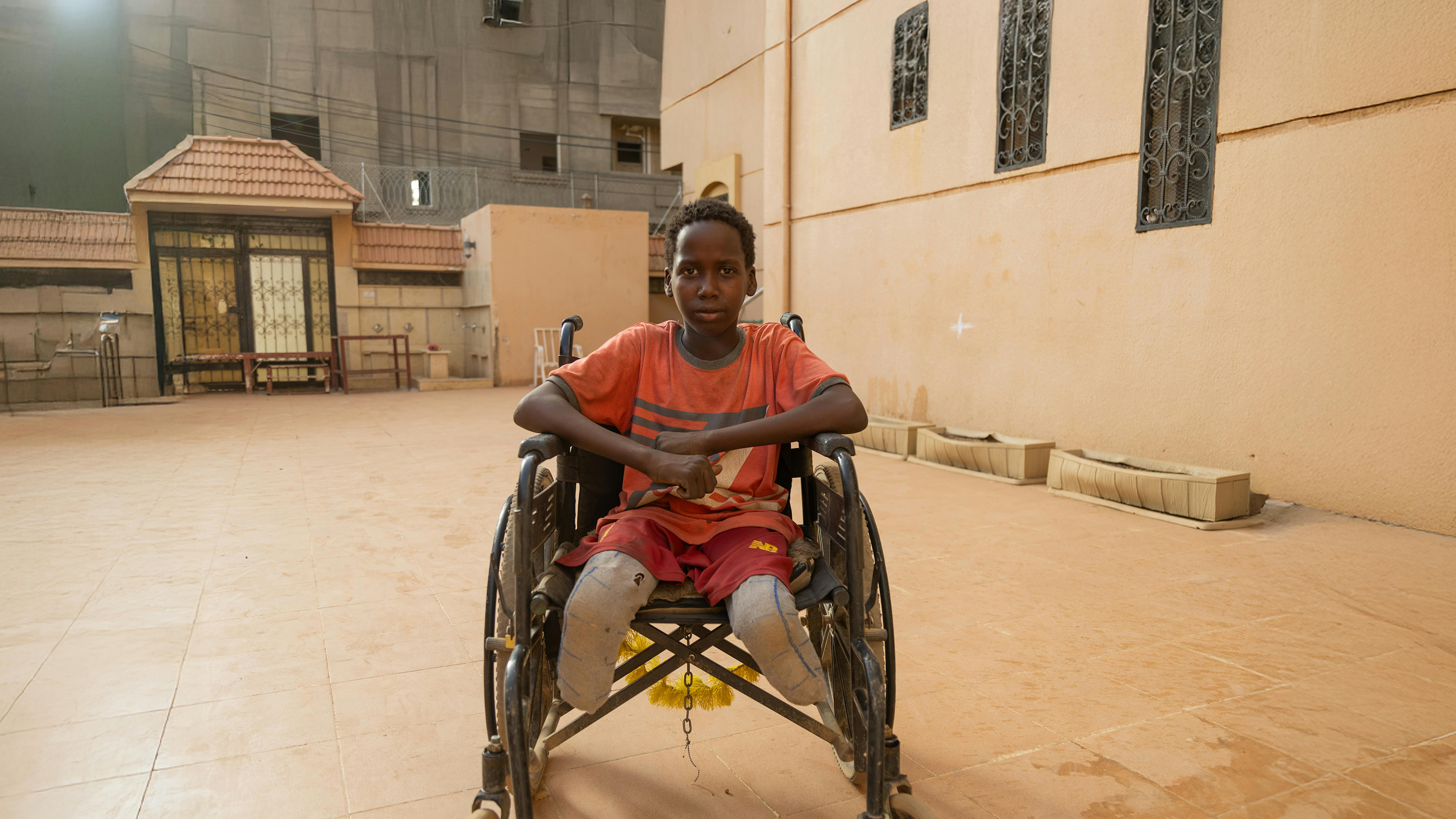 Zuhair, 12 anni, siede nel complesso della sua casa a Khartoum.  La vita di Zuhair cambiò il giorno in cui una bomba colpì la sua casa, e un pezzo di scheggia gli attraversò il corpo.
