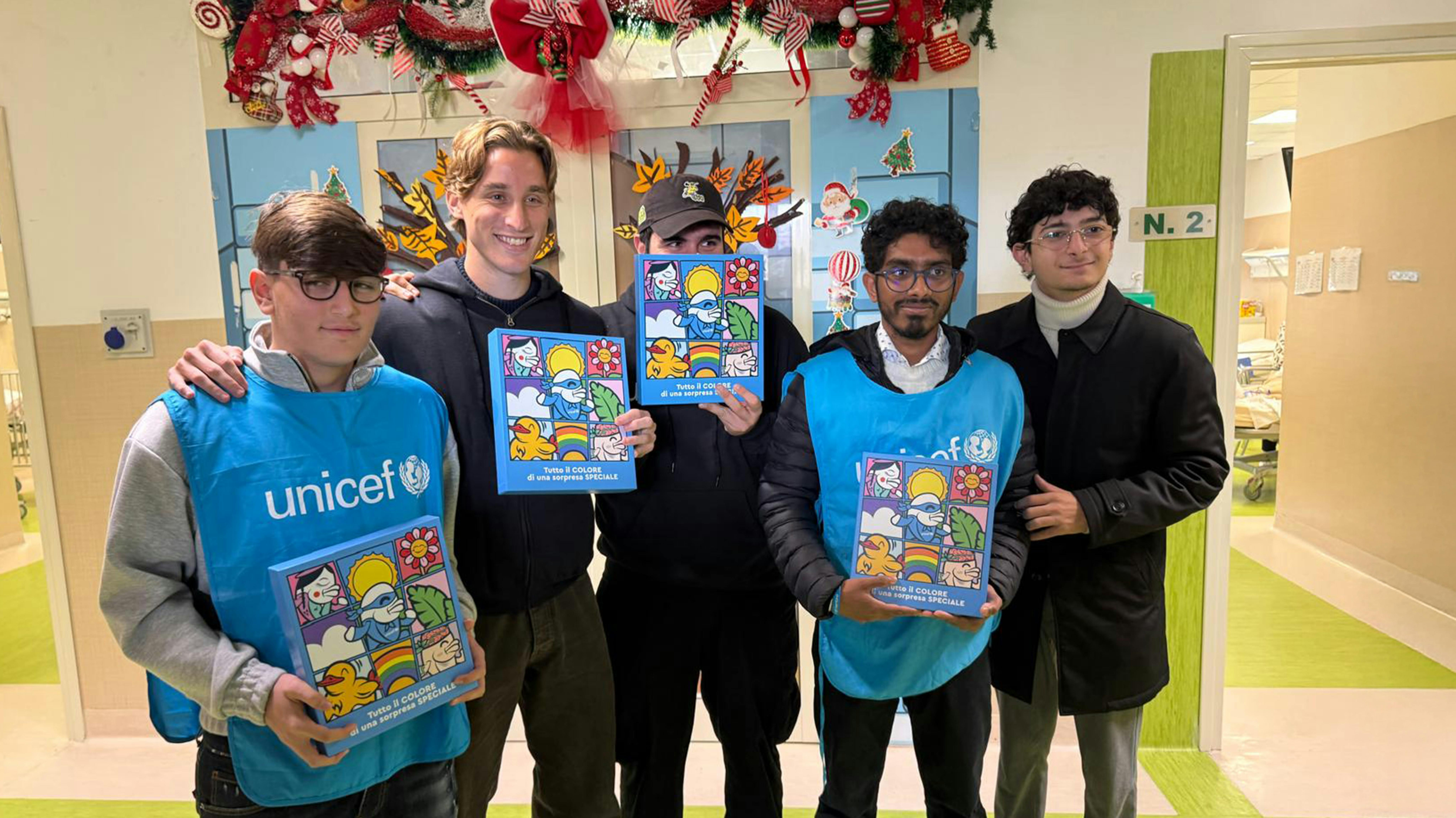 Volontari UNICEF durante la consegna del regalo sospeso all'Ospedale Santonono Pausilipon, il secondo da sinistra è il calciatore Edoardo Bove e il terzo lo street artist Merioone