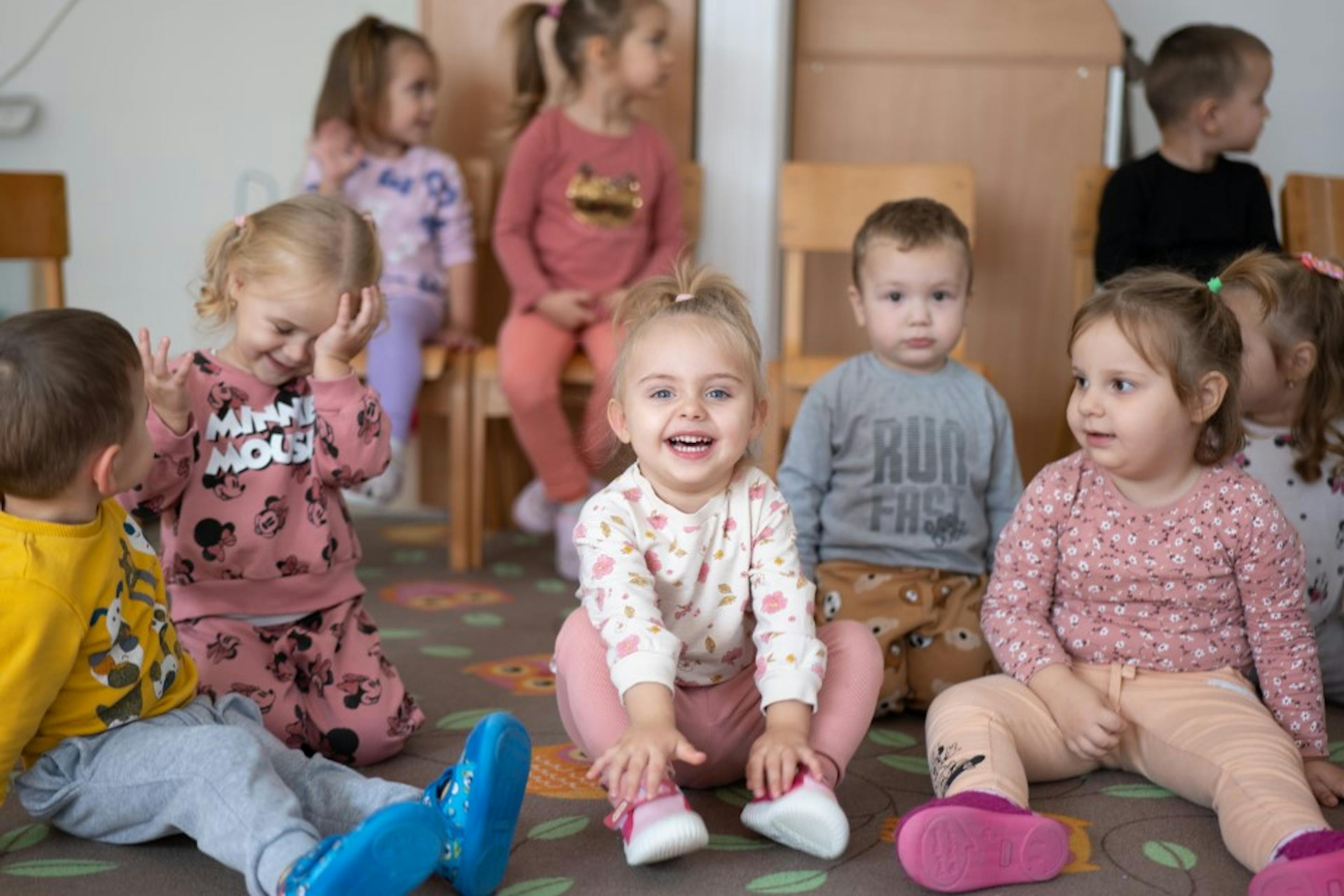 Una bambina sorride, circondata dai suoi compagni di asilo