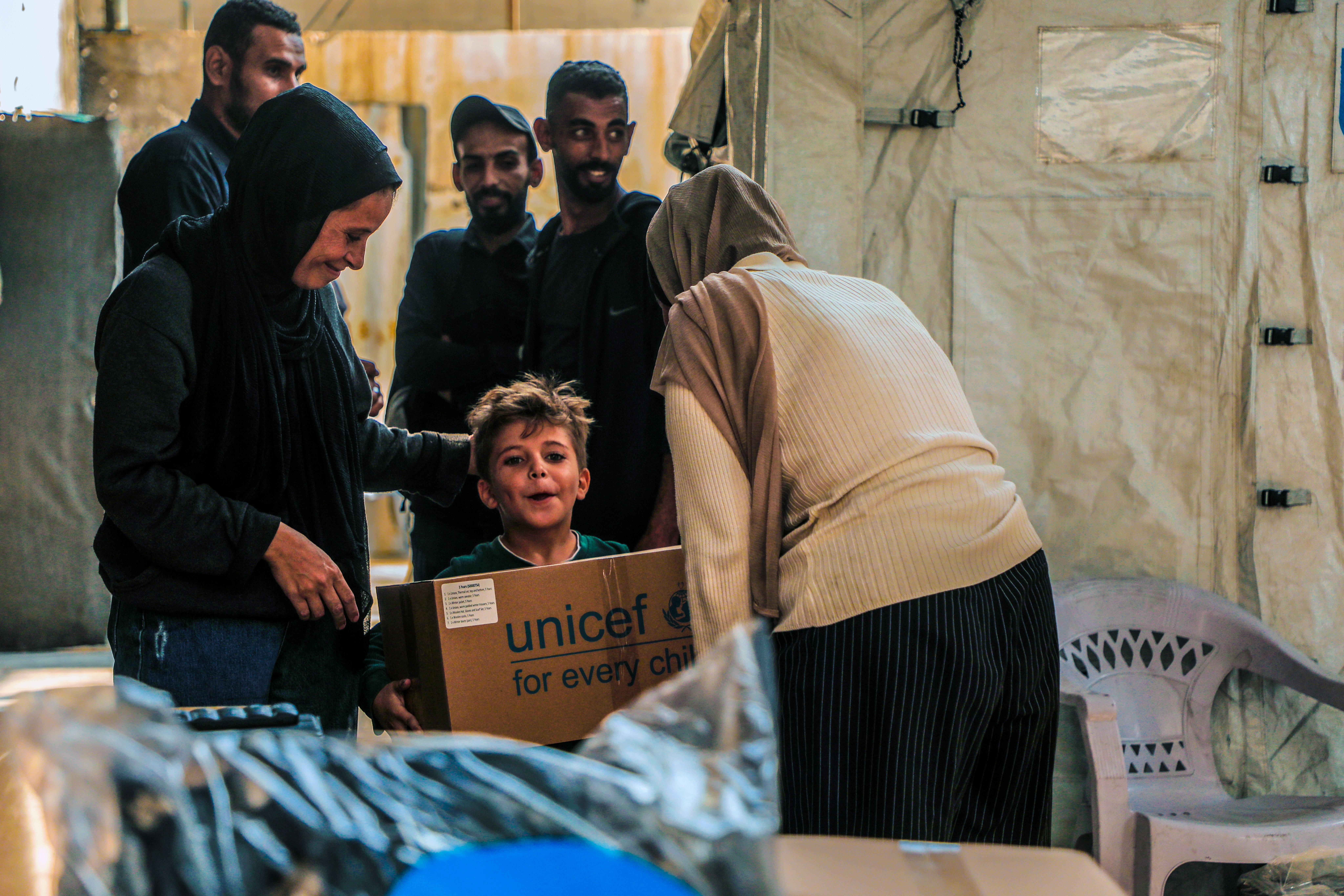 Un bambino riceve un pacco di aiuti per l'inverno, presso il Women’s Programs Center nella parte occidentale di Gaza City. Siamo nel novembre 2025