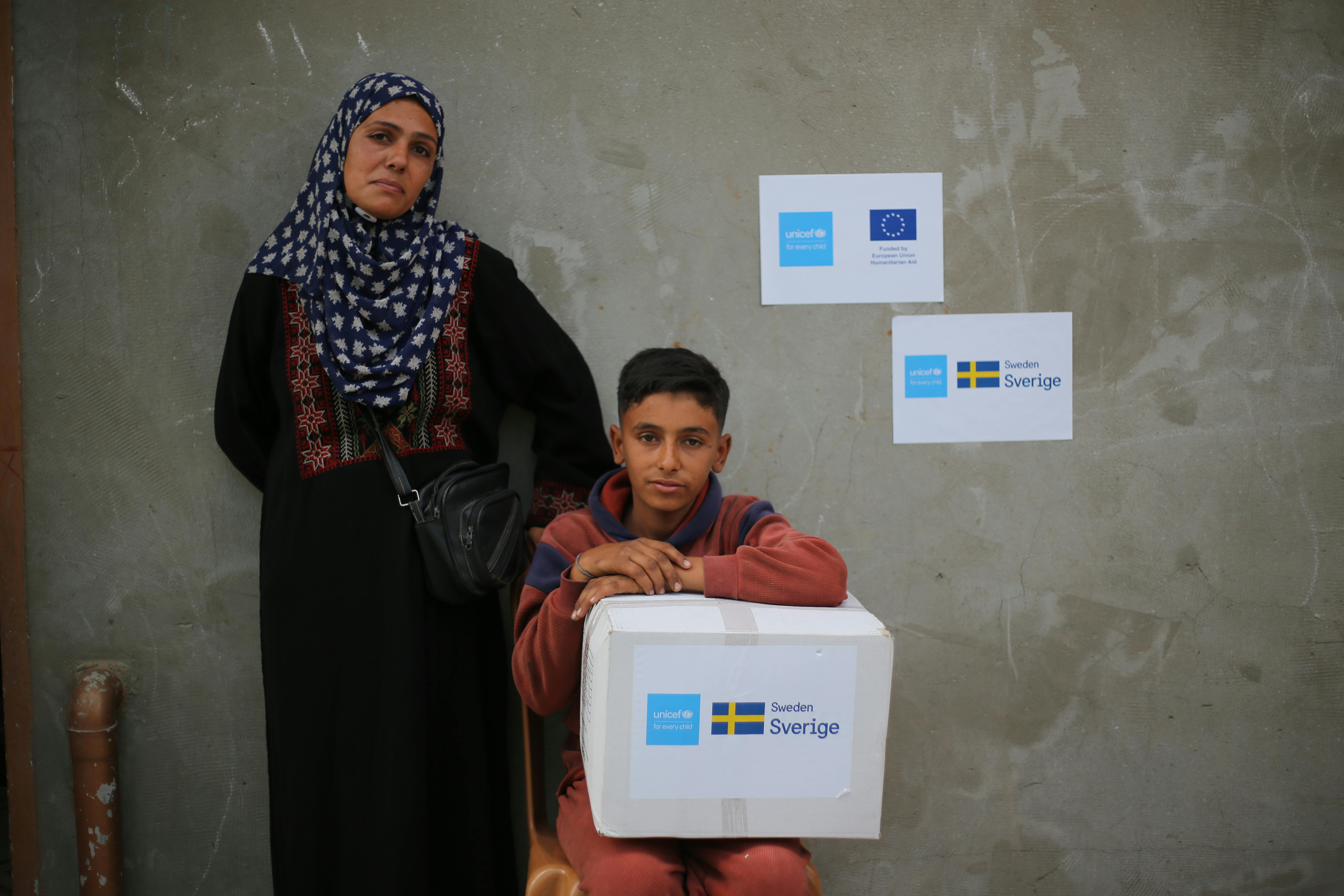 Ahmed, 13 anni, posa con la madre Falasteen dopo aver ricevuto un pacco di aiuti UNICEF per l'inverno. Siamo nel campo sfollati di Deir al-Balah, Striscia di Gaza