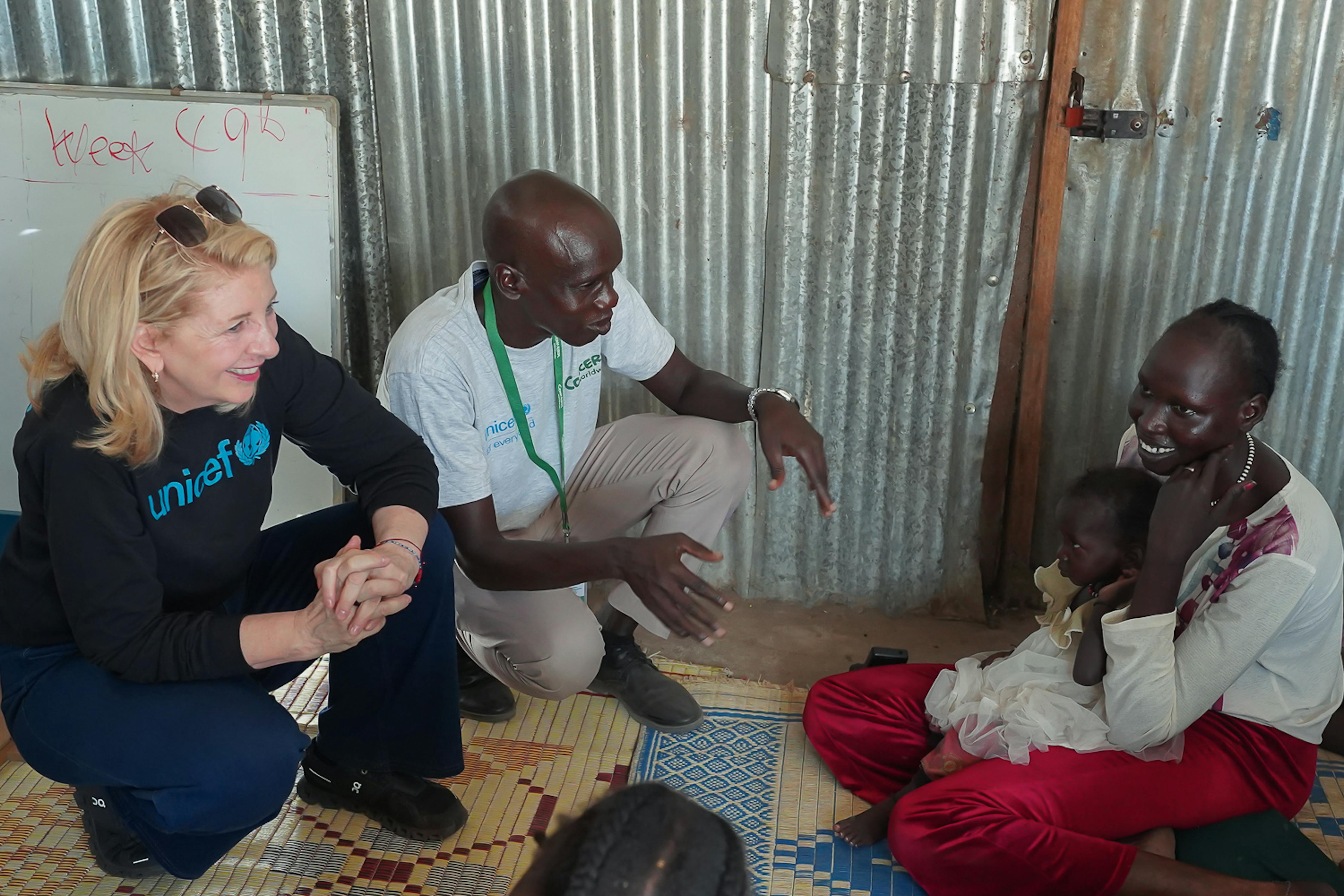 Il 5 dicembre 2025 a Bentiu, nel Sud Sudan, la direttrice esecutiva dell'UNICEF Catherine Russell parla con la madre Nyachar Mai, 23 anni, che tiene in braccio la figlia di 18 mesi, Nyalinga, durante una visita al Nutrition Site E nel campo di Bieh per sfollati interni