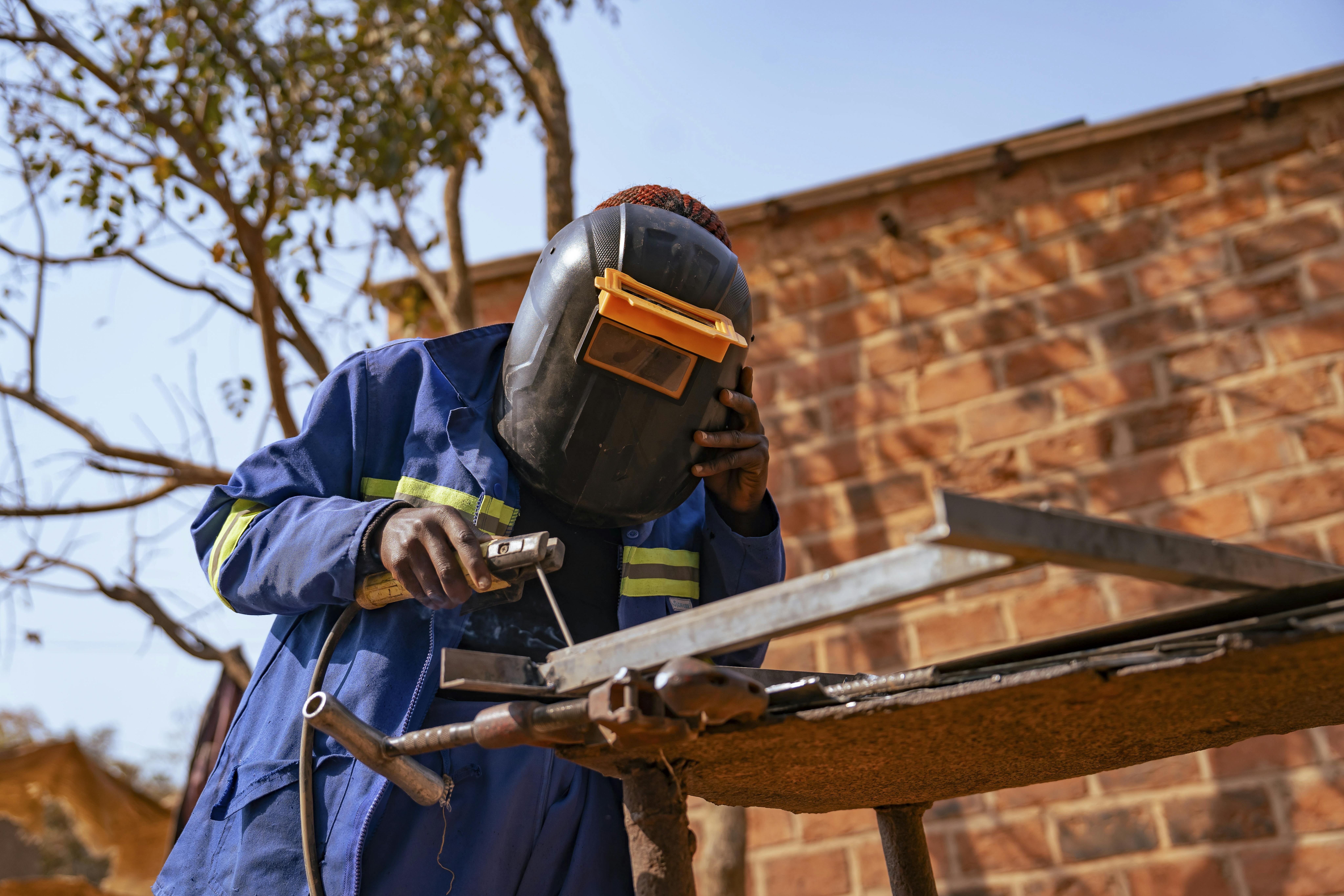 Astride, 16 anni, salda una cornice di finestra in un cortile all’aperto che funge da officina a Tshala, nella provincia di Lualaba, Repubblica Democratica del Congo