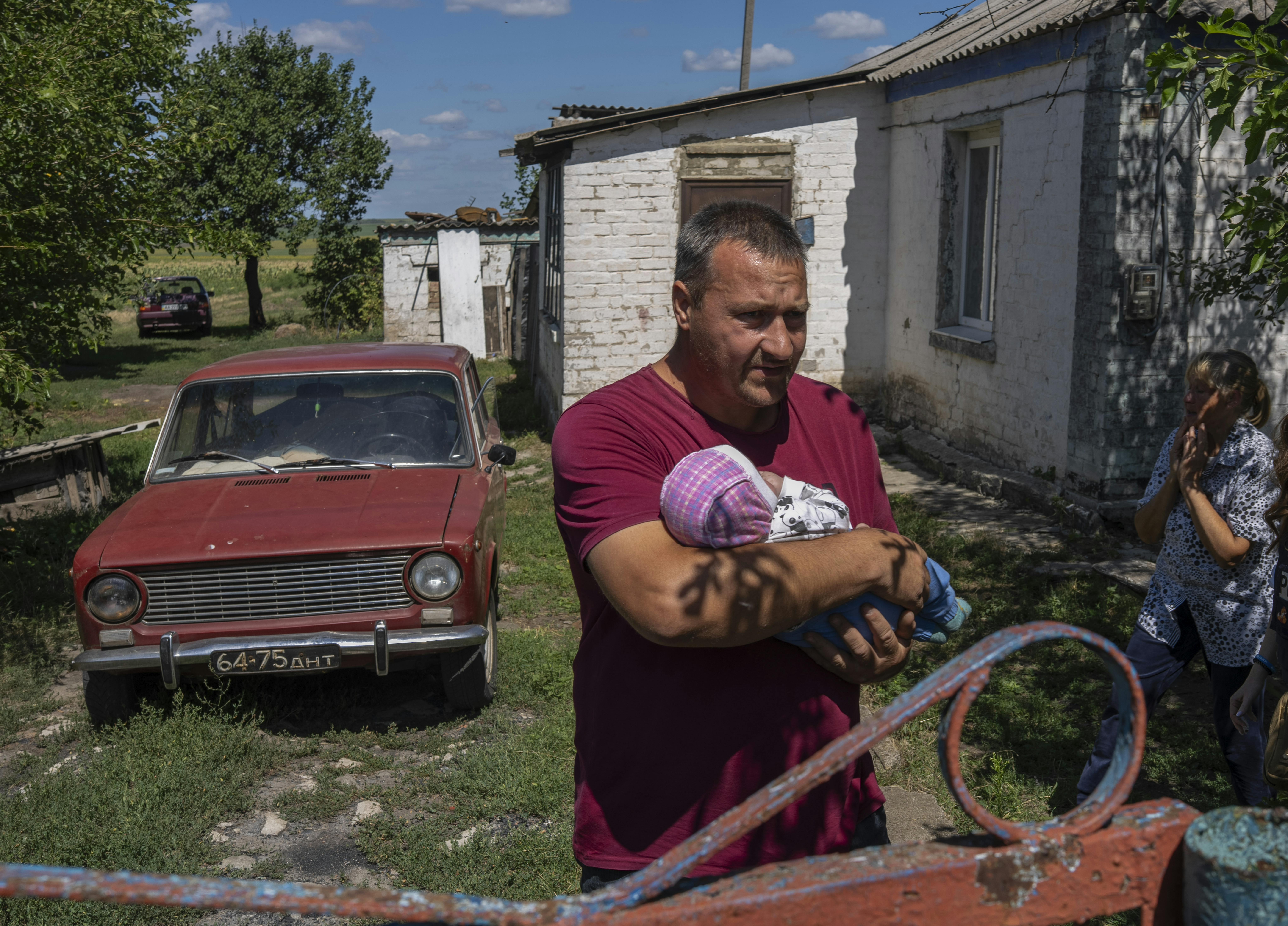 Ucraina. Oleksii, 43 anni, tiene in braccio il figlio di tre mesi mentre si prepara a salire su un autobus per l'evacuazione umanitaria con la sua famiglia. Dietro di lui, l'anziana madre si rifiuta di lasciare la loro casa nonostante il crescente pericolo dei bombardamenti nelle vicinanze.