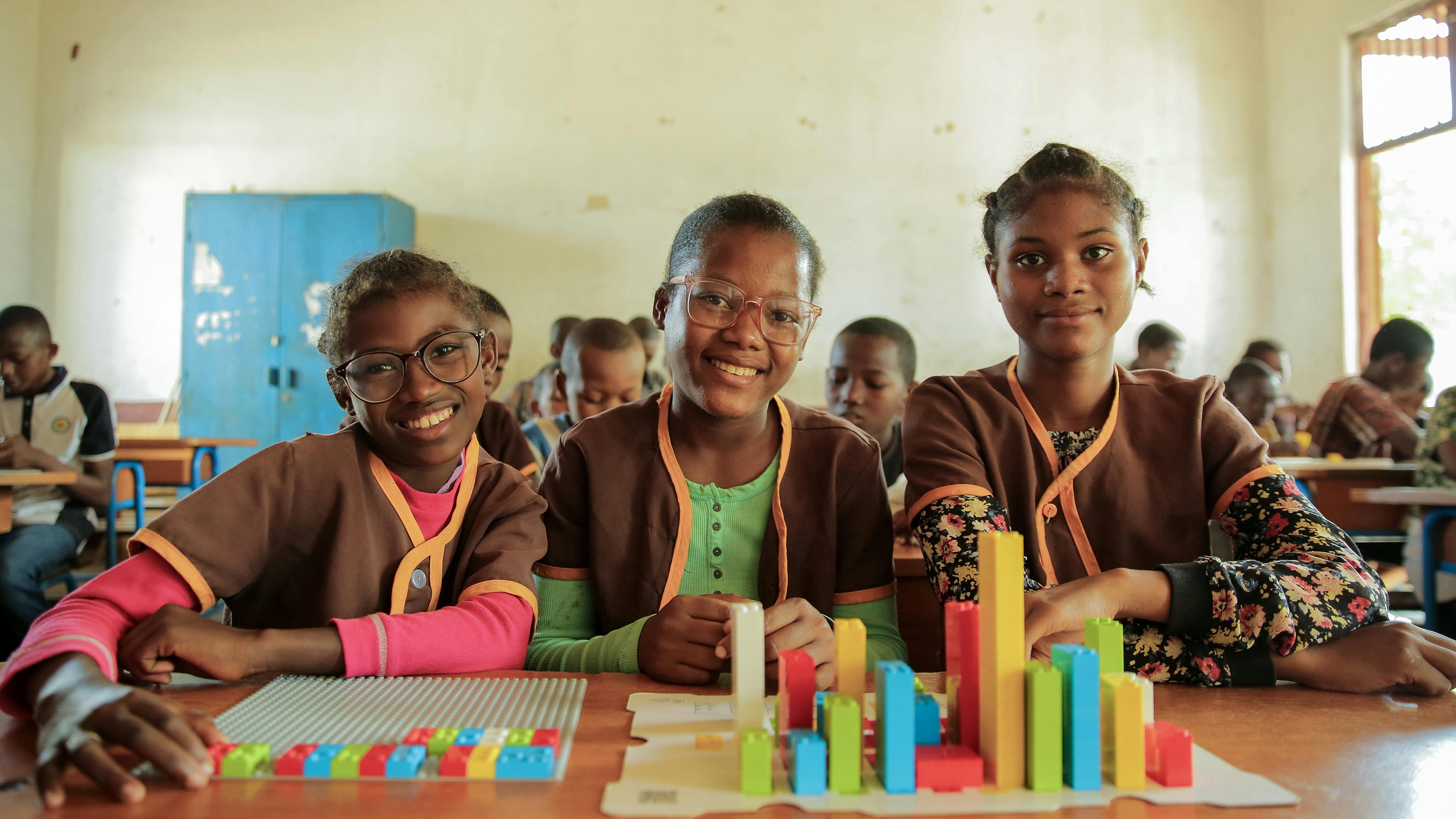 Alexandra, sul lato sinistro, 12 anni, che ha problemi di vista, insieme ai suoi compagni di classe, usa i mattoncini LEGO Braille (LBB)