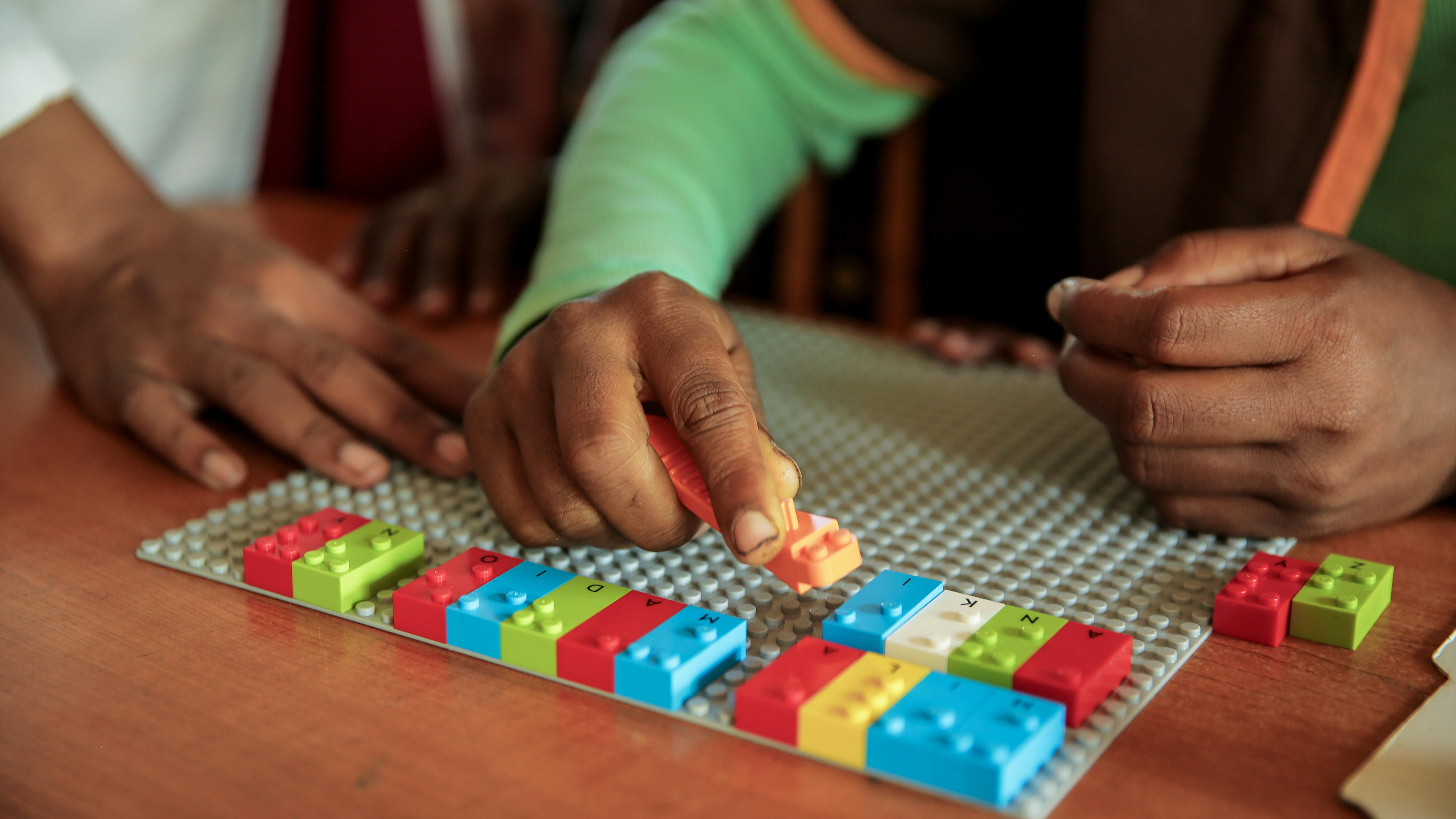 Studenti utilizzano i mattoncini LEGO Braille (LBB) per scrivere una frase su un banco scolastico, in un'aula della scuola primaria Impitiny, Farafangana, Regione di Fitovinany, Madagascar