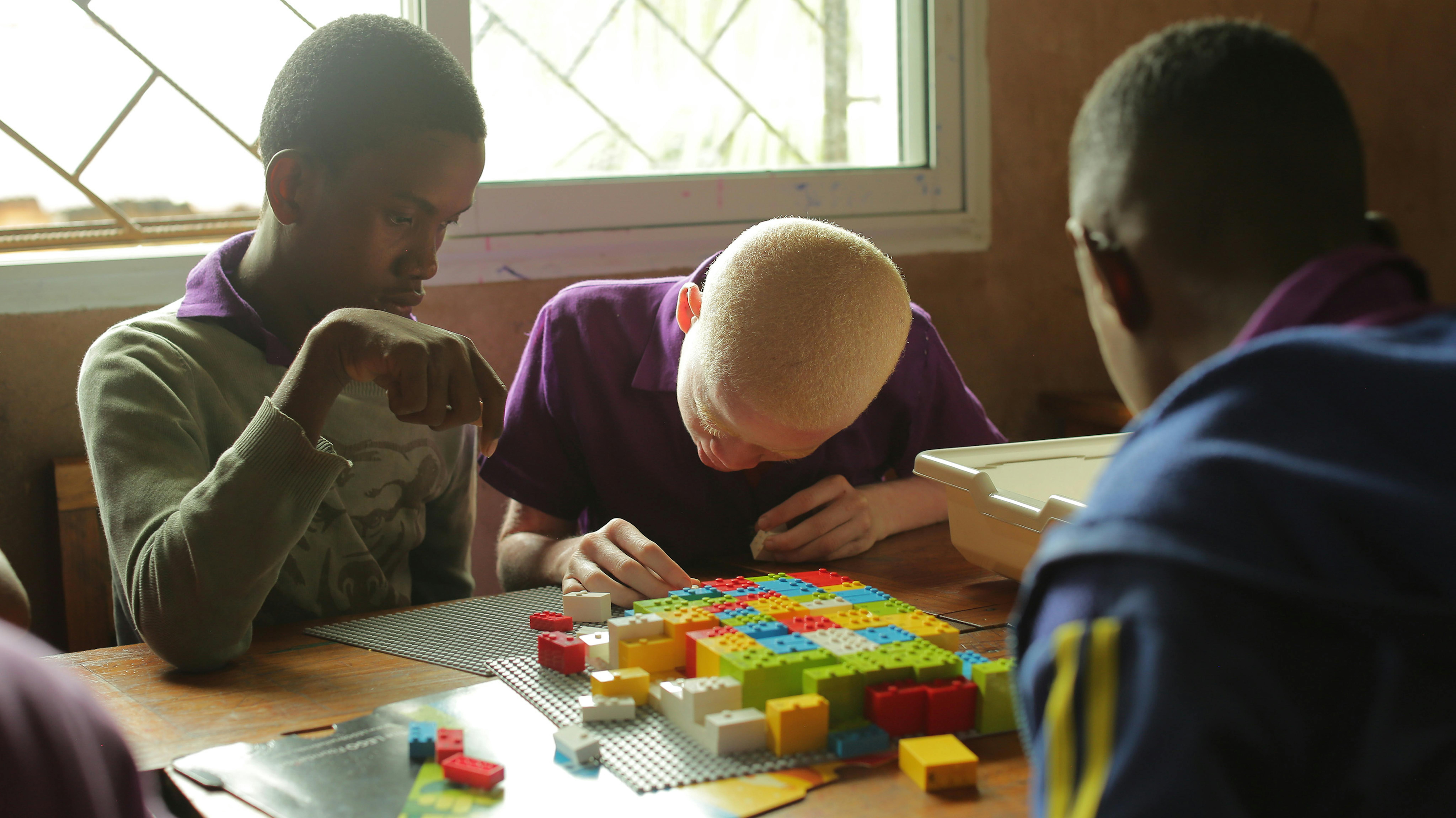 Due studenti di quinta utilizzano i mattoncini LEGO Braille per imparare a leggere e scrivere Braille durante una lezione di malgascio
