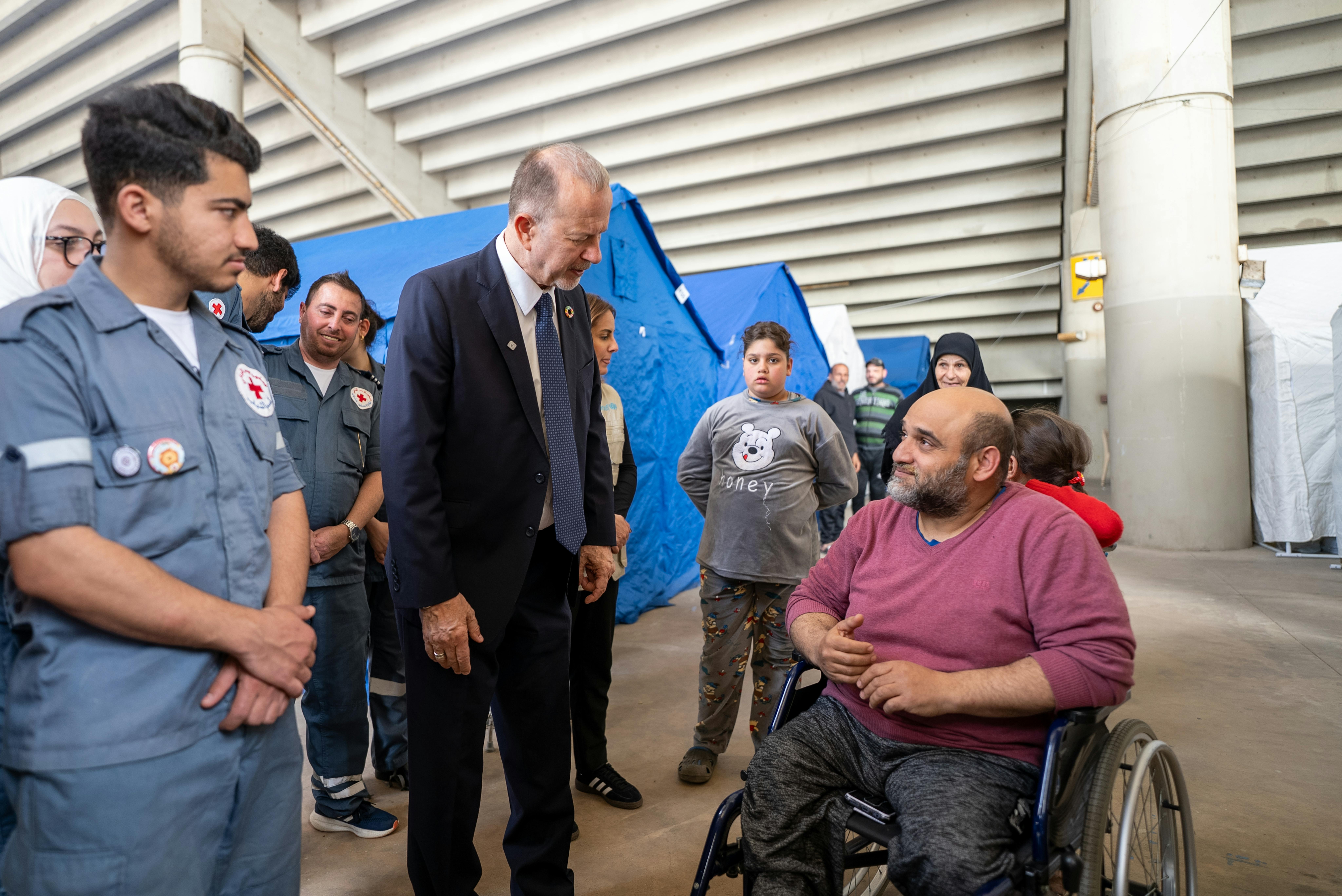 Ted Chaiban parla con un uomo sfollato durante la visita al sito di accoglienza di Sports City a Beirut. Insieme a UNICEF Libano e alla Croce Rossa Libanese, ha osservato i sistemi di registrazione, distribuzione e i servizi igienico-sanitari presenti nel sito.