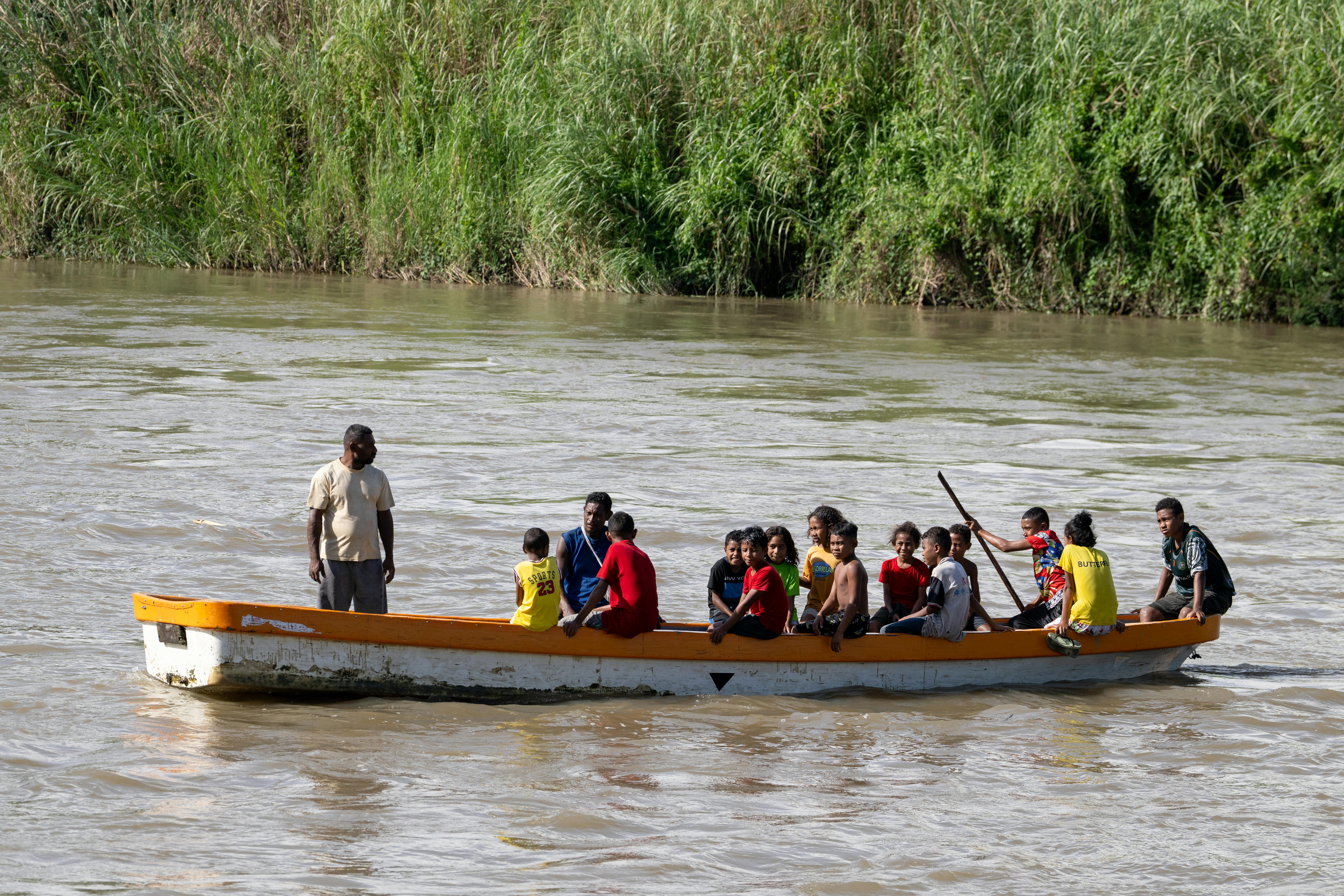 I bambini più piccoli attraversano il fiume con un piccolo barchino per andare a scuola. Siamo in Papua Nuova Guinea  dove le alluvioni hanno distrutto l'unico ponte della comunità
