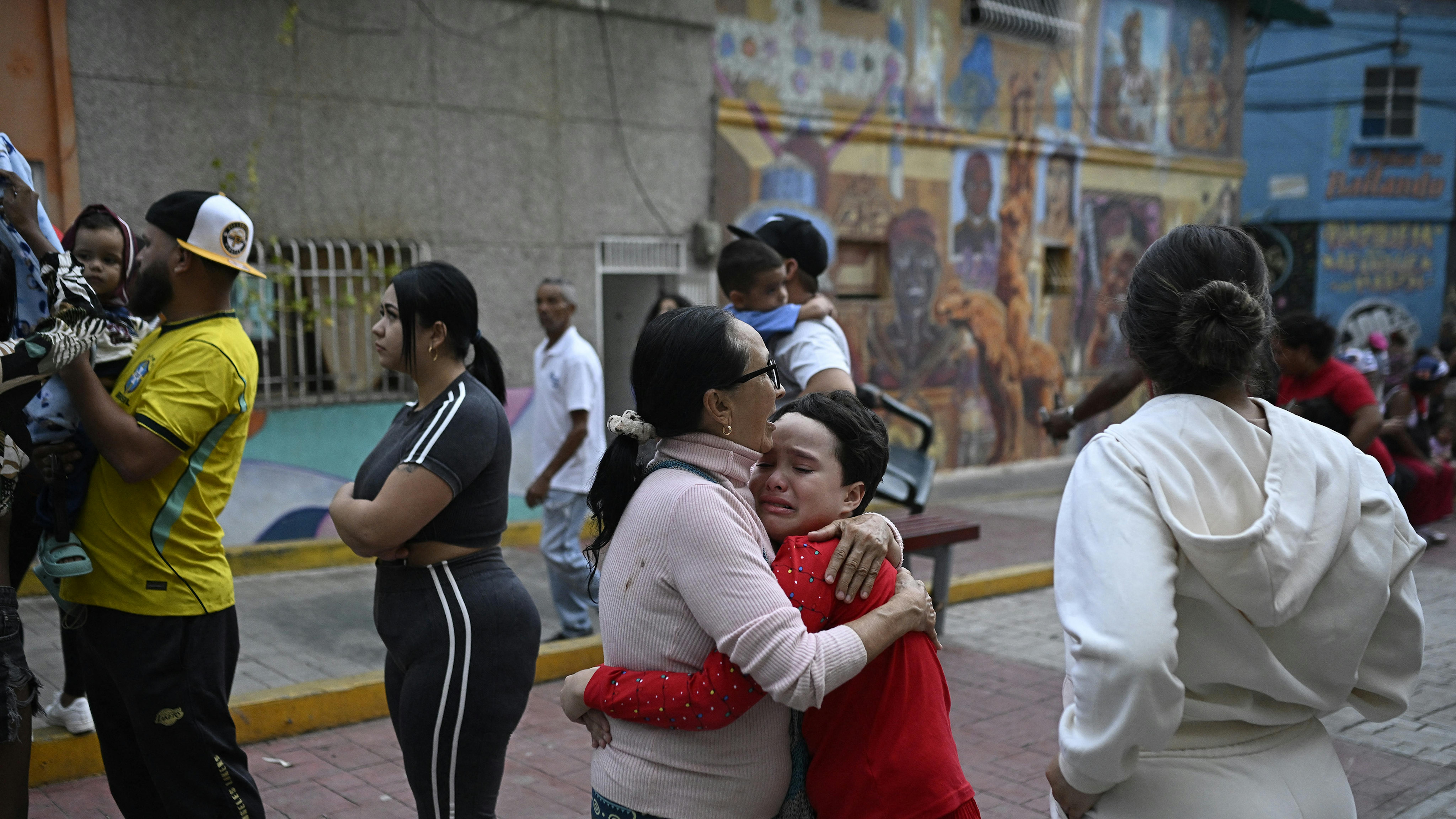Venezuela - Una donna consola un bambino in strada dopo il terremoto a Caracas del 24 giugno 2026.