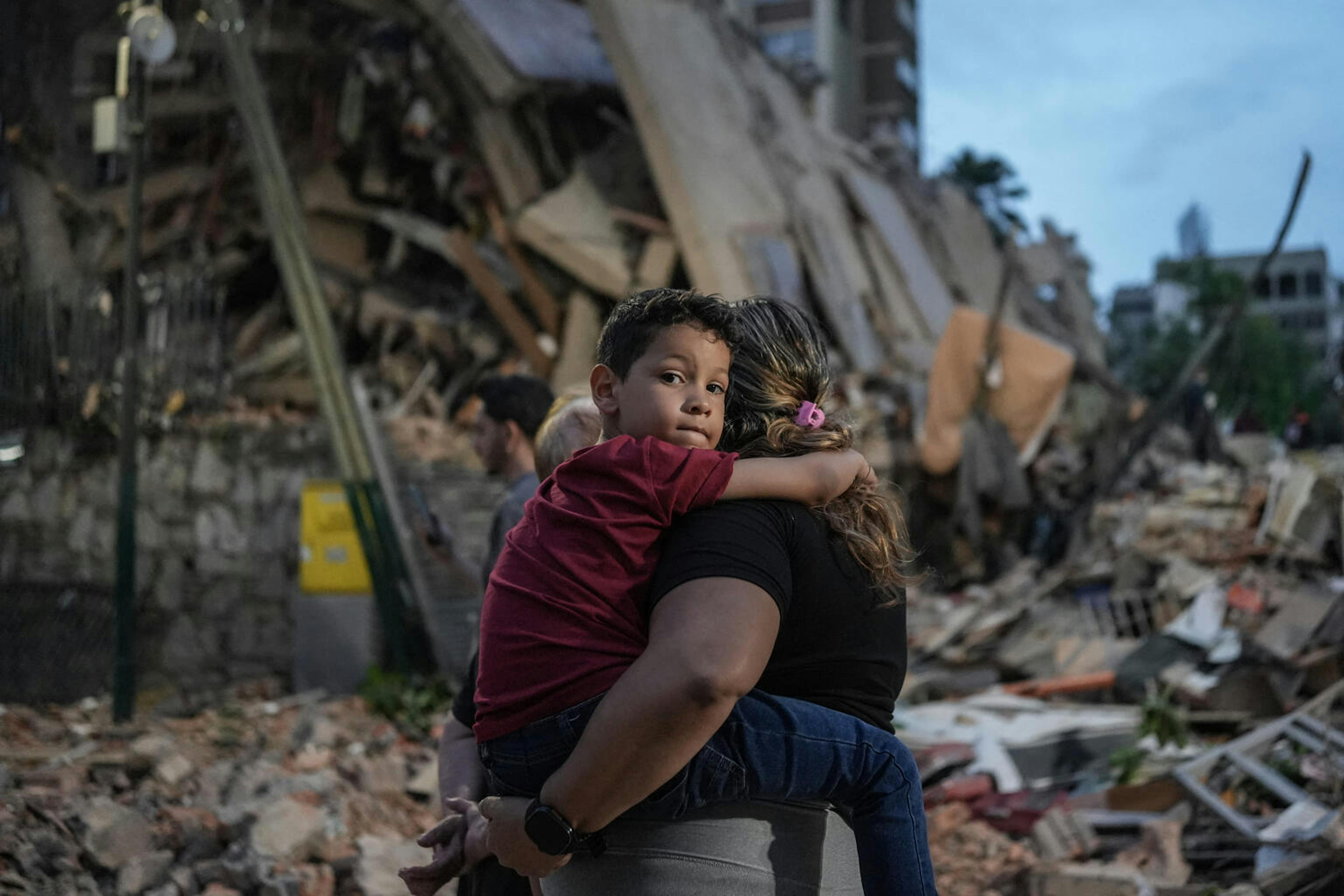 Venezuela, un bambino in braccio a una donna con le macerie del terremoto sullo sfondo