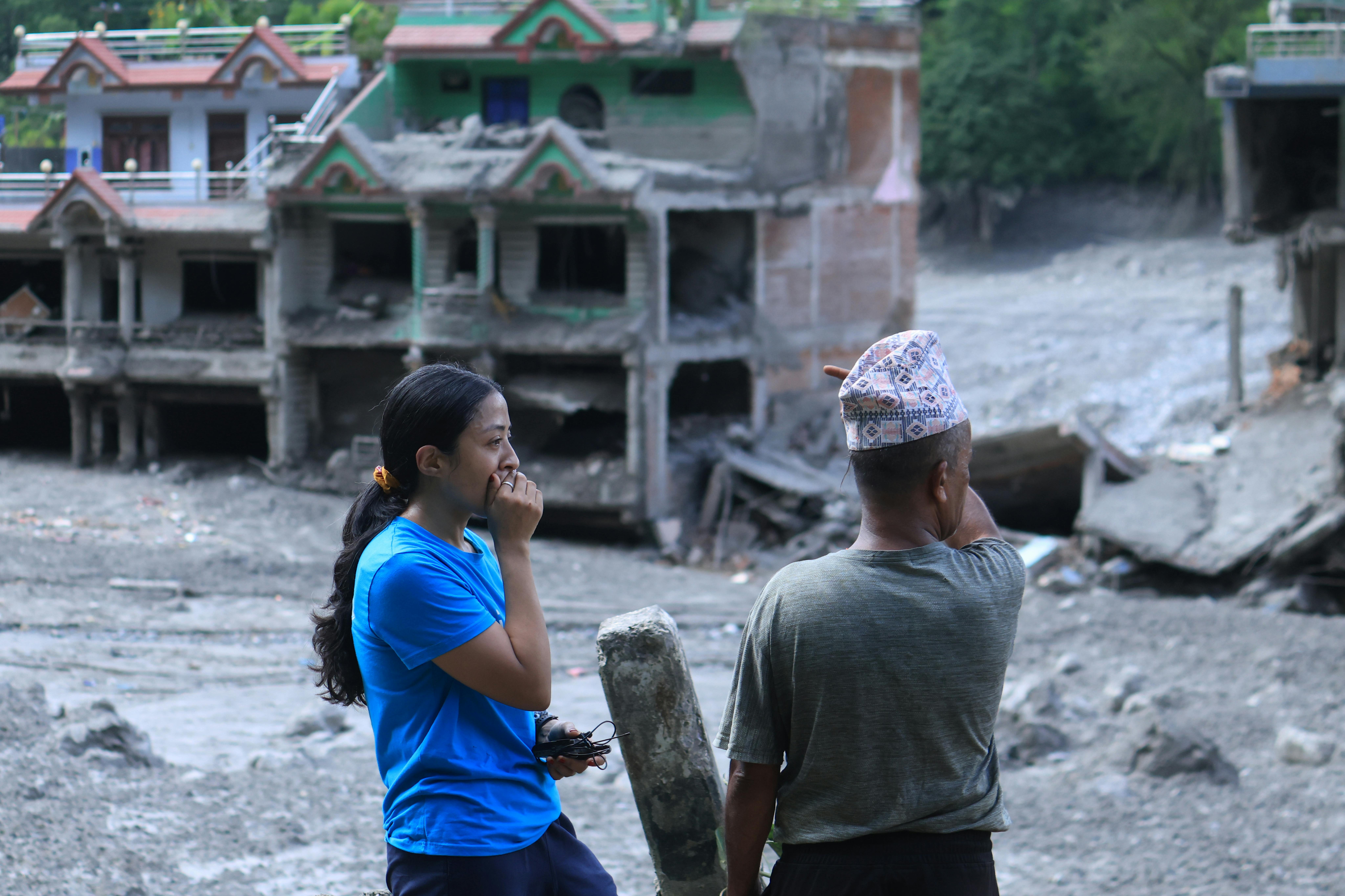 Un'operatrice UNICEF parla con un membro della comunità nell'area di Nuwakot, provincia di Bagmati, in Nepal. Sullo sfondo si vedono case e strade ricoperte di fango a seguito dell'alluvione del 26 agosto