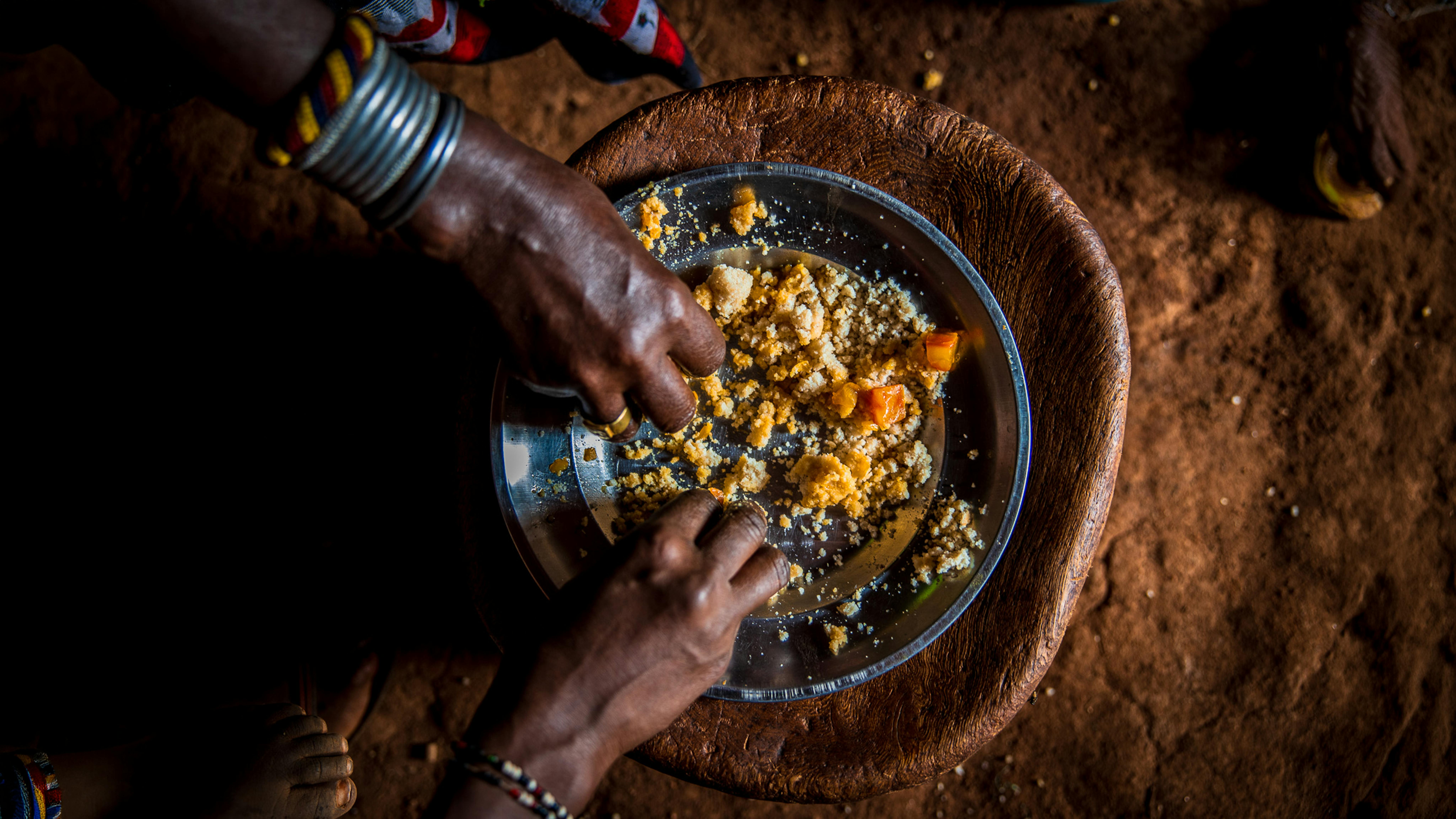 Godana e i suoi figli consumano un pasto nel rifugio temporaneo della famiglia. Grazie all’assistenza in denaro dell’UNICEF, può acquistare cibo e garantire nuovamente un’alimentazione adeguata ai propri figli.