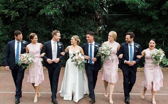 Couple with their bridesmaids and groomsmen linking arms