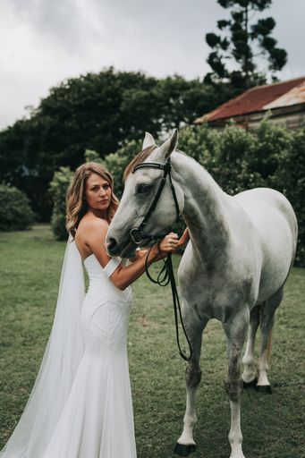 Bride looks sultry while posing with grey horse