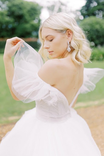 Bride wearing white gown with a plunging backline and ruffled open shoulders
